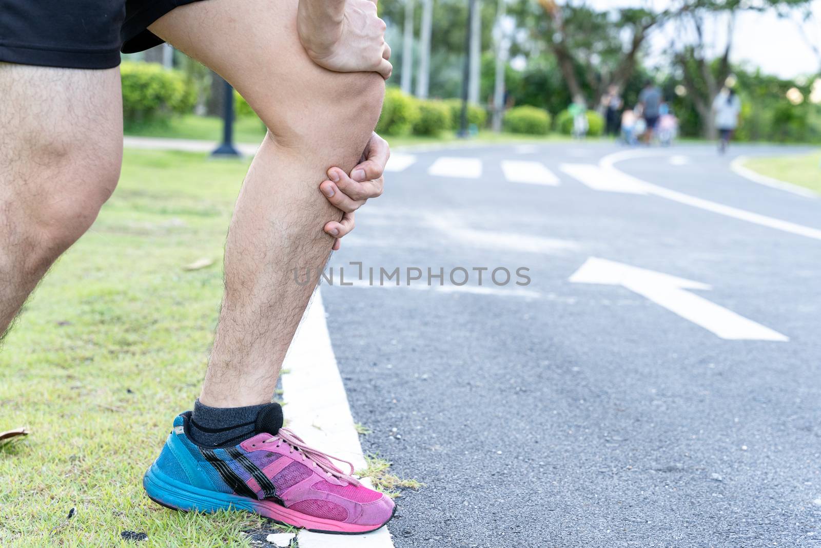Asian man use hands hold on his knee injury while running on road in the park, Injury from workout concept.