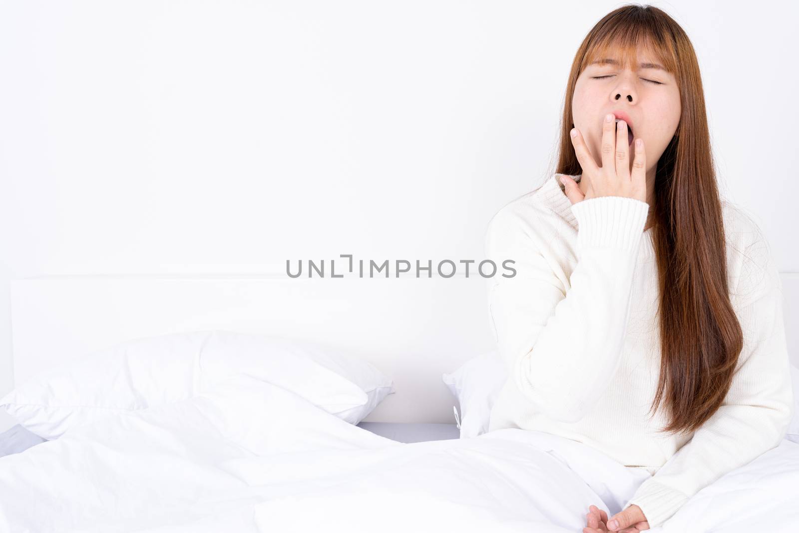 Asian woman are yawning covering open mouth with hand after she wake up. Healthcare medical or daily life concept. by mikesaran