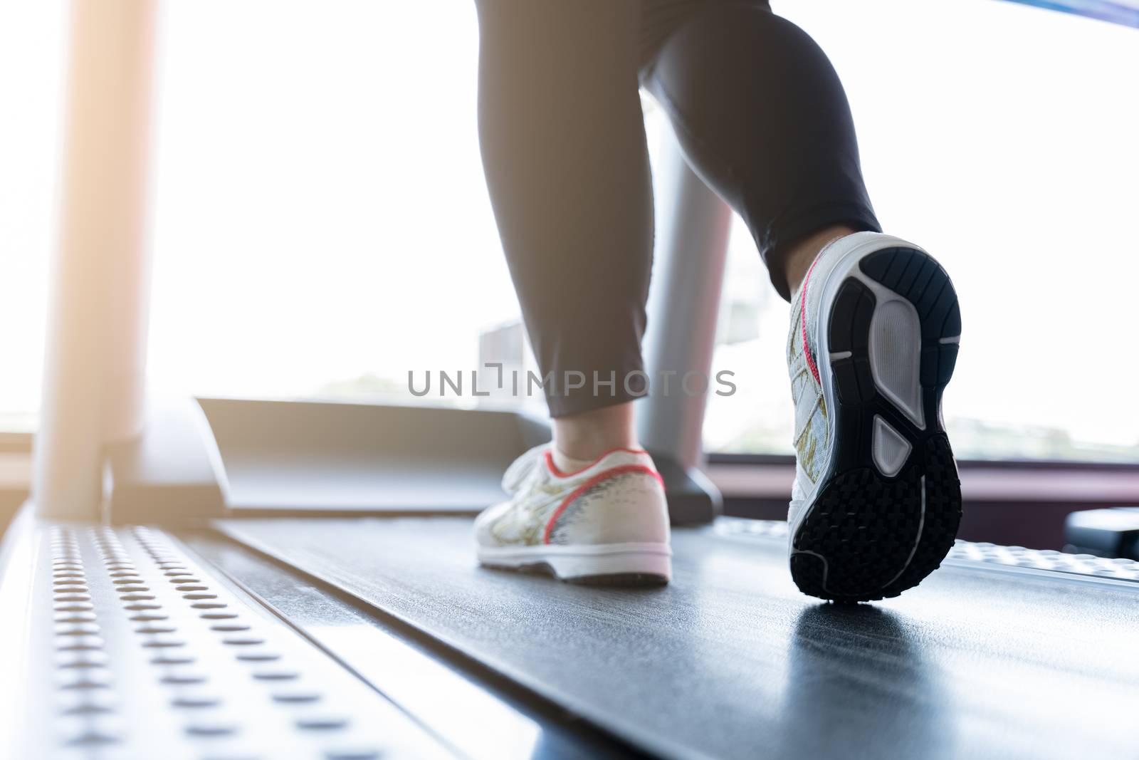 Close up female feet wearing sneakers running on treadmill at fitness gym. Diet lifestyle, weight loss, stomach muscle, healthy concept.