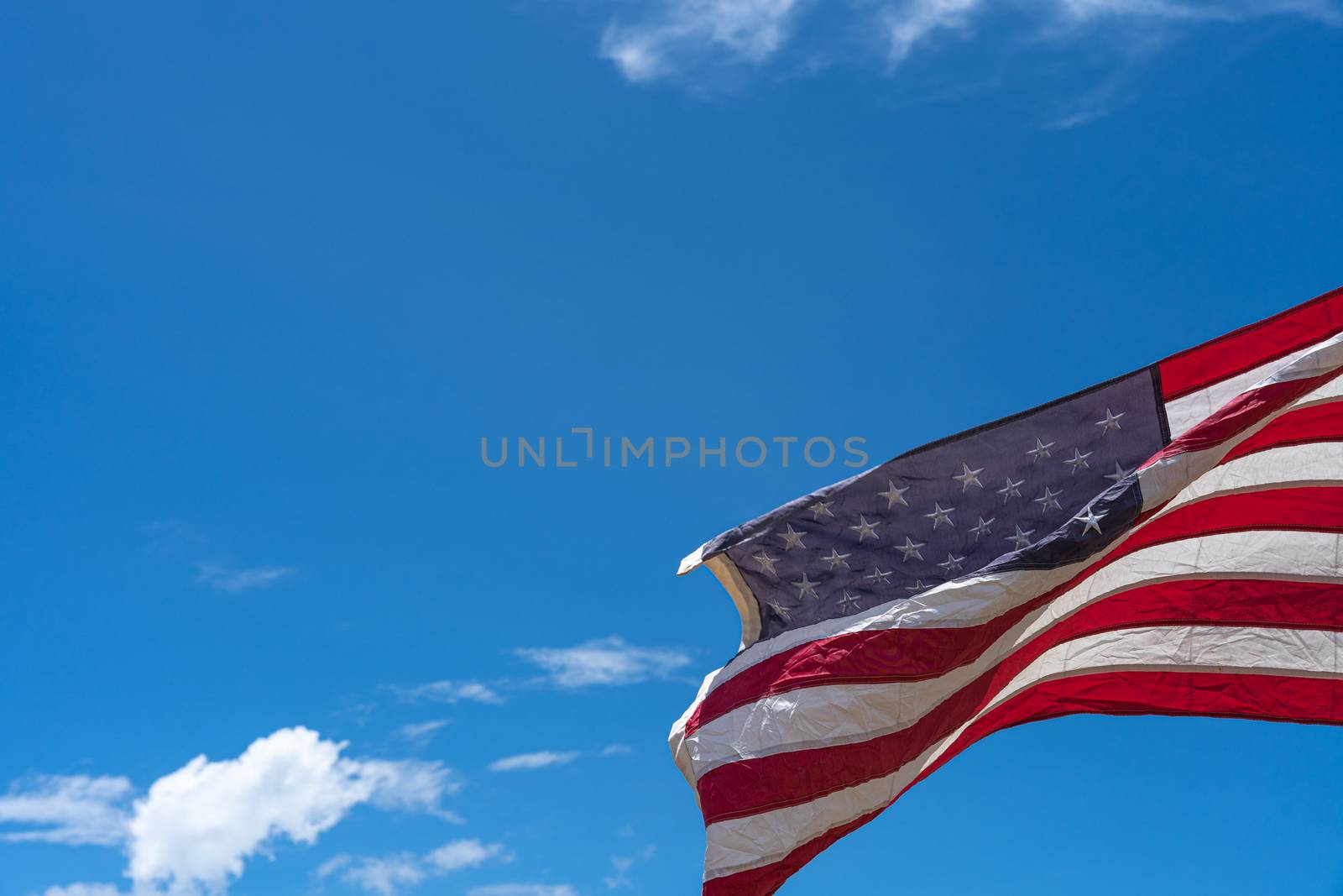 Waving USA flag under blue sky background. by mikesaran