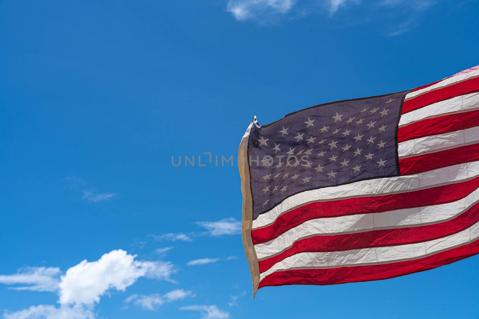 Waving USA flag under blue sky background. by mikesaran