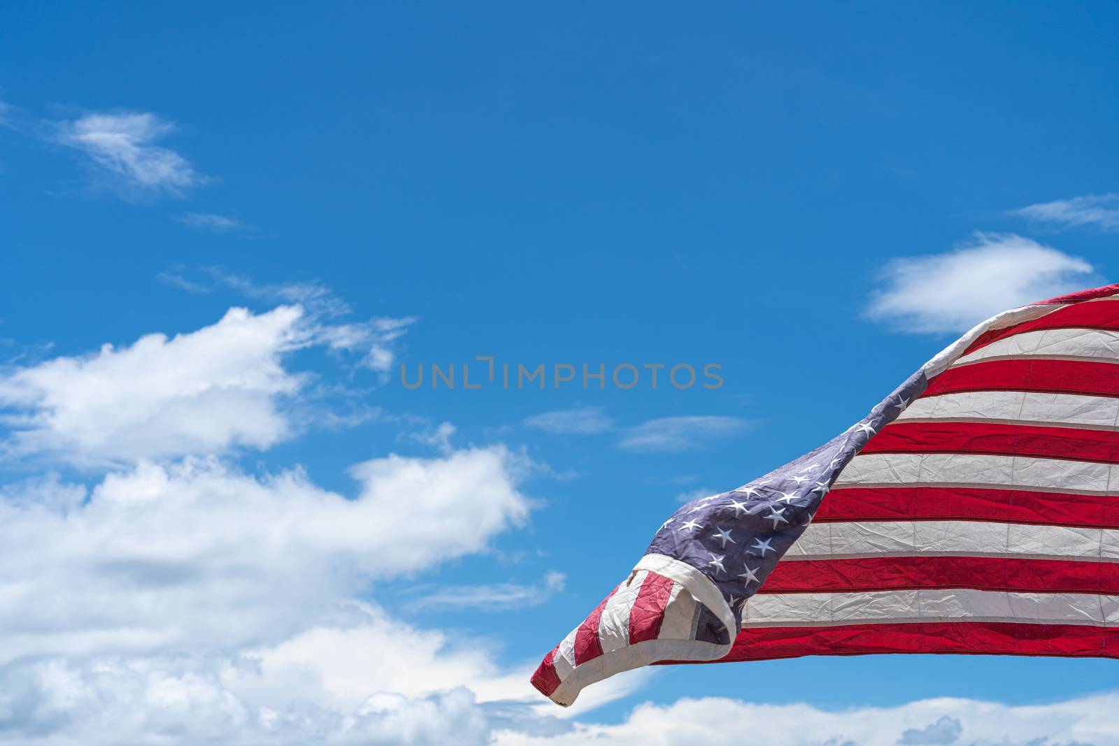 Waving USA flag under blue sky background.