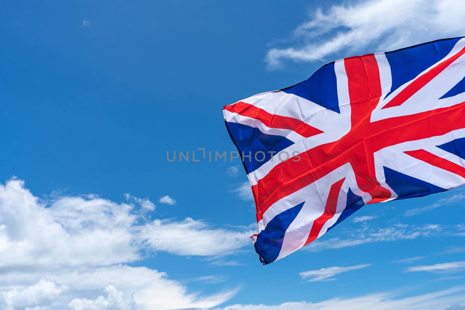 Waving UK flag under blue sky background. by mikesaran