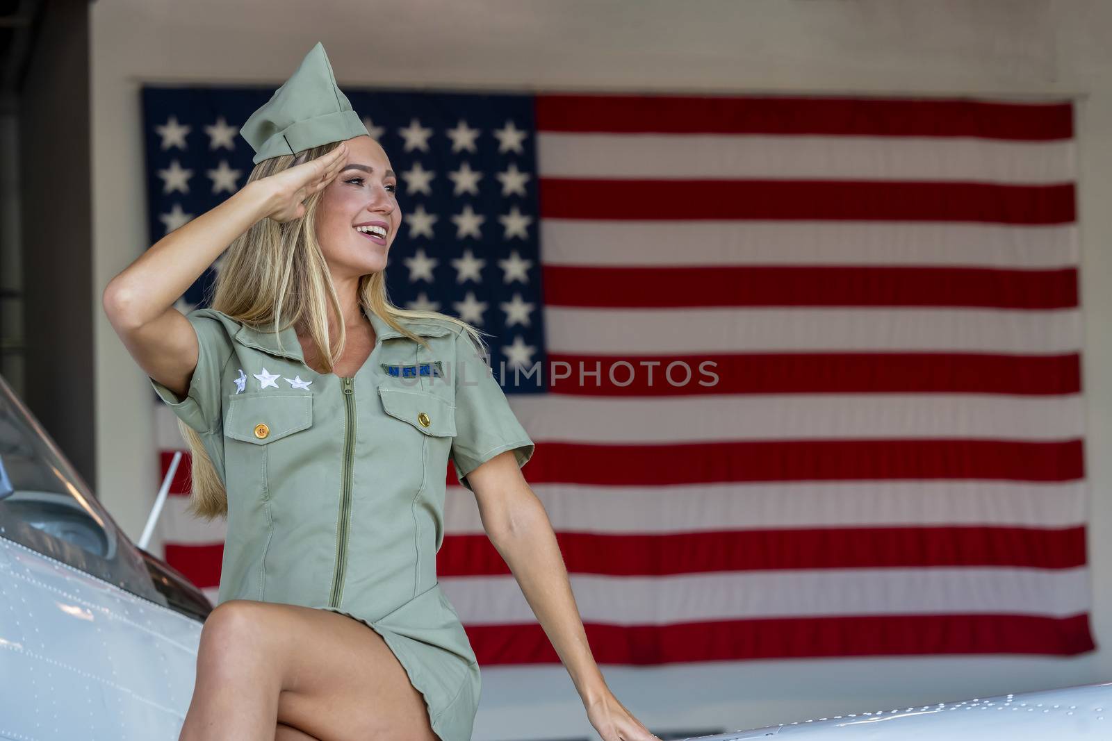 A beautiful blonde model poses with a vintage WWII aircraft