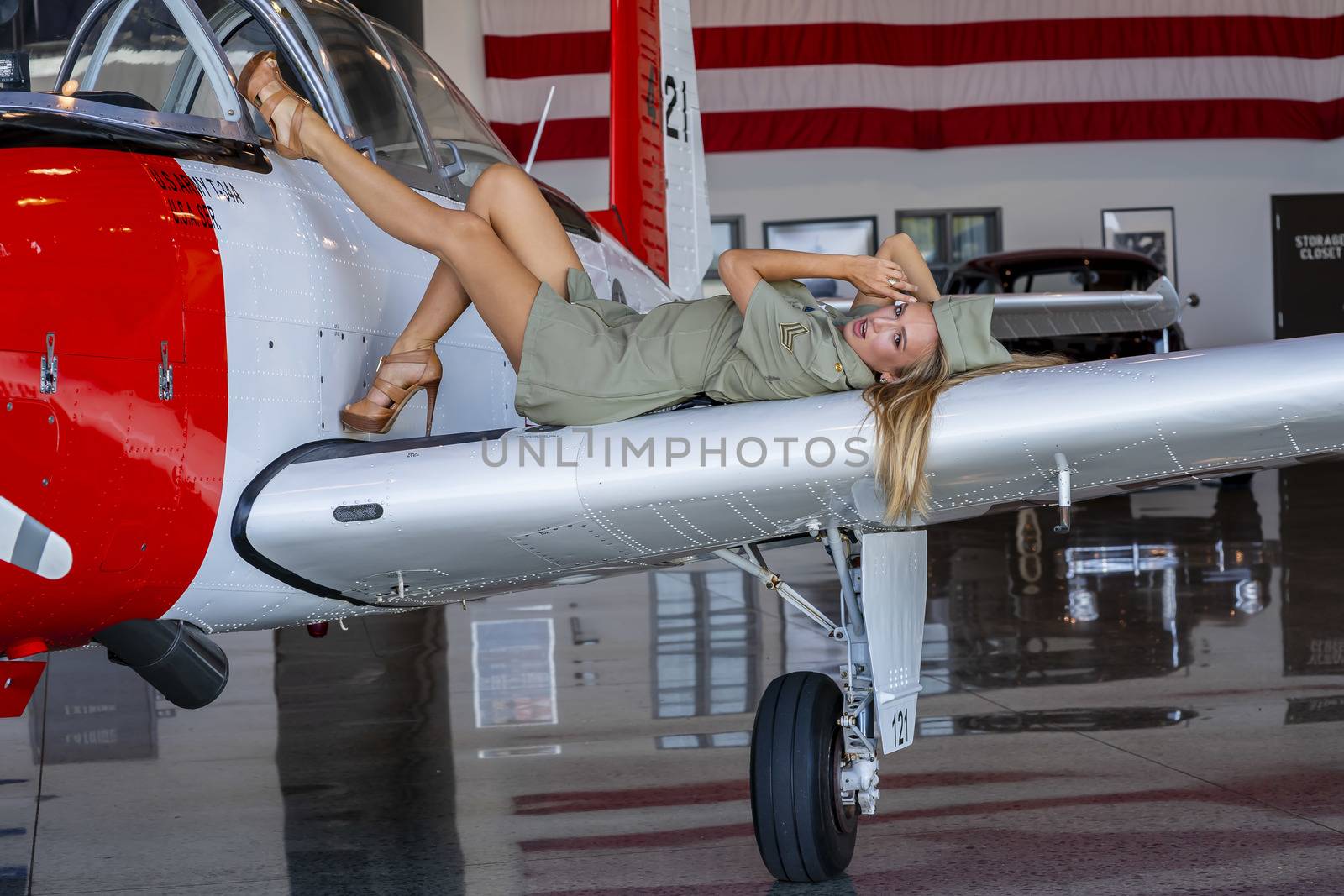 A beautiful blonde model poses with a vintage WWII aircraft