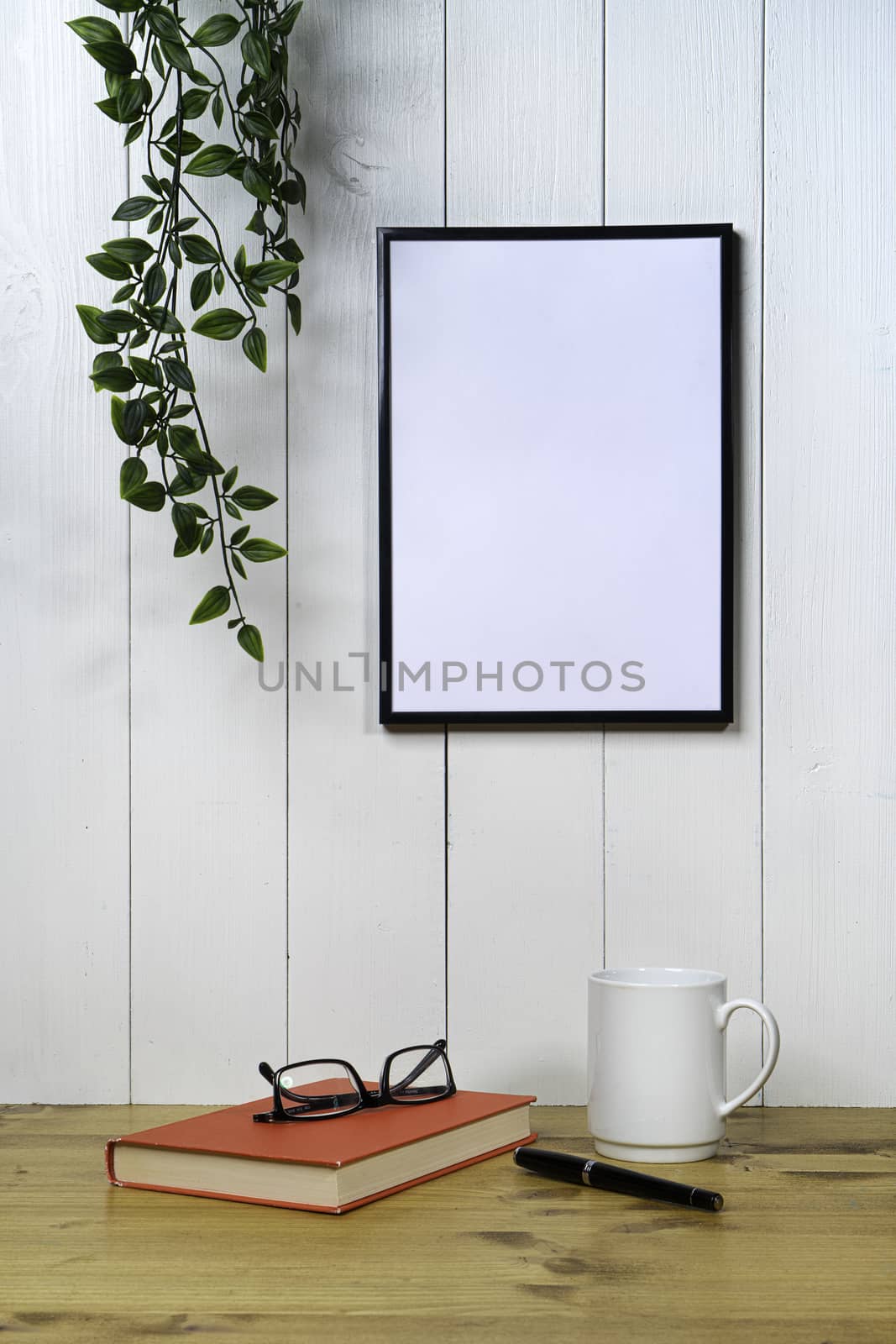 one blank black frame  and an ivy  on a white wood background