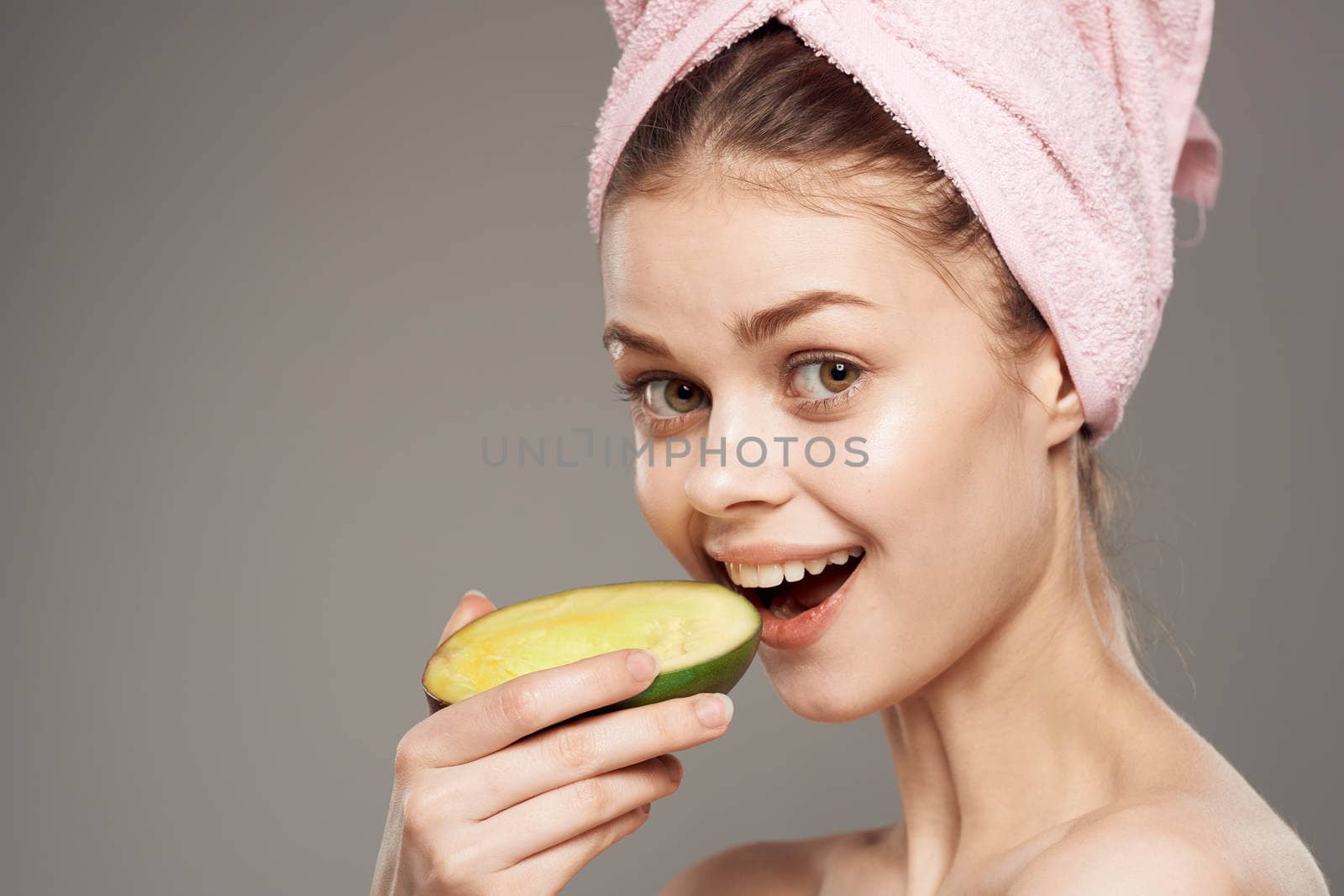 Pretty woman holding a mango in her hand a pink towel on her head close-up. High quality photo