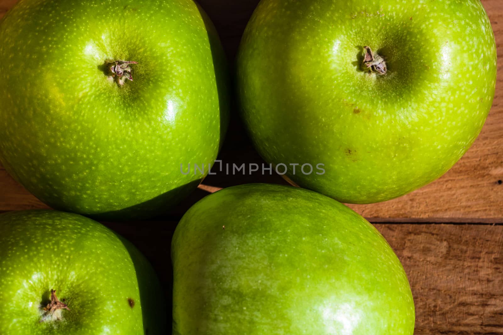 Detail on ripe green apples on wooden table. by vladispas