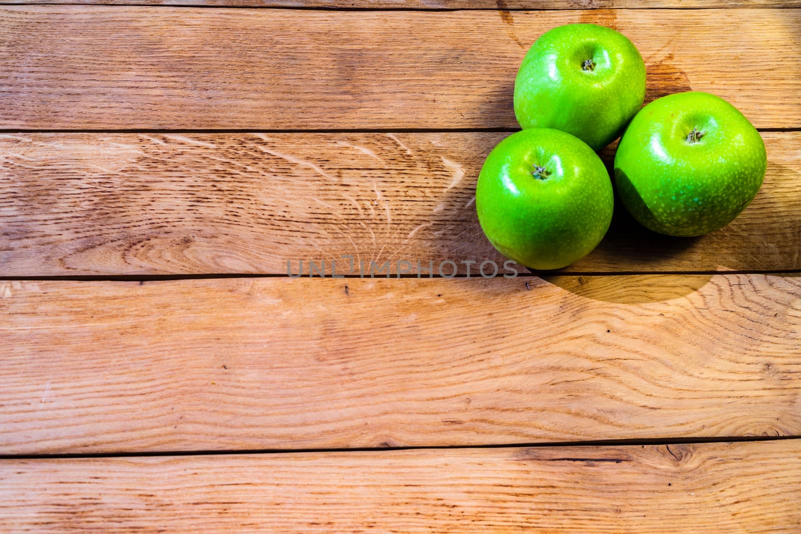 Detail on ripe green apples on wooden table.