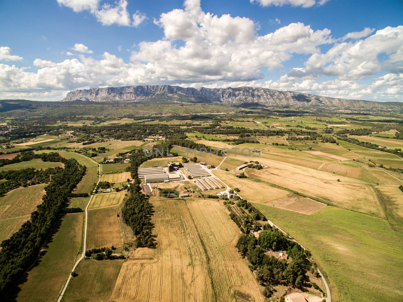 Aerial view of farm field with big farm in South of France. Big farm land during summer dry season next the mountain.