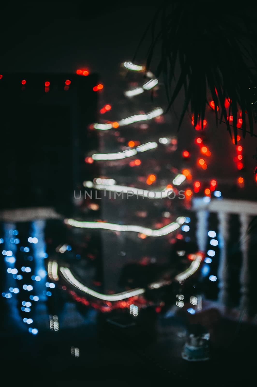 Decorated Christmas tree on the street close-up. Red balls and garland backlit with lanterns. New Year's baubles macro photo with bokeh. Winter holiday light decoration