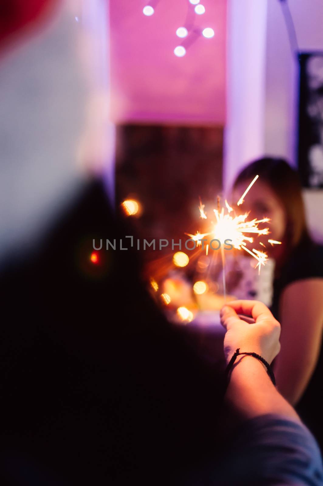 girl transfers sparkler to her friend at Christmas celebration, party. Concept of winter holidays and fun. by Alla_Morozova93
