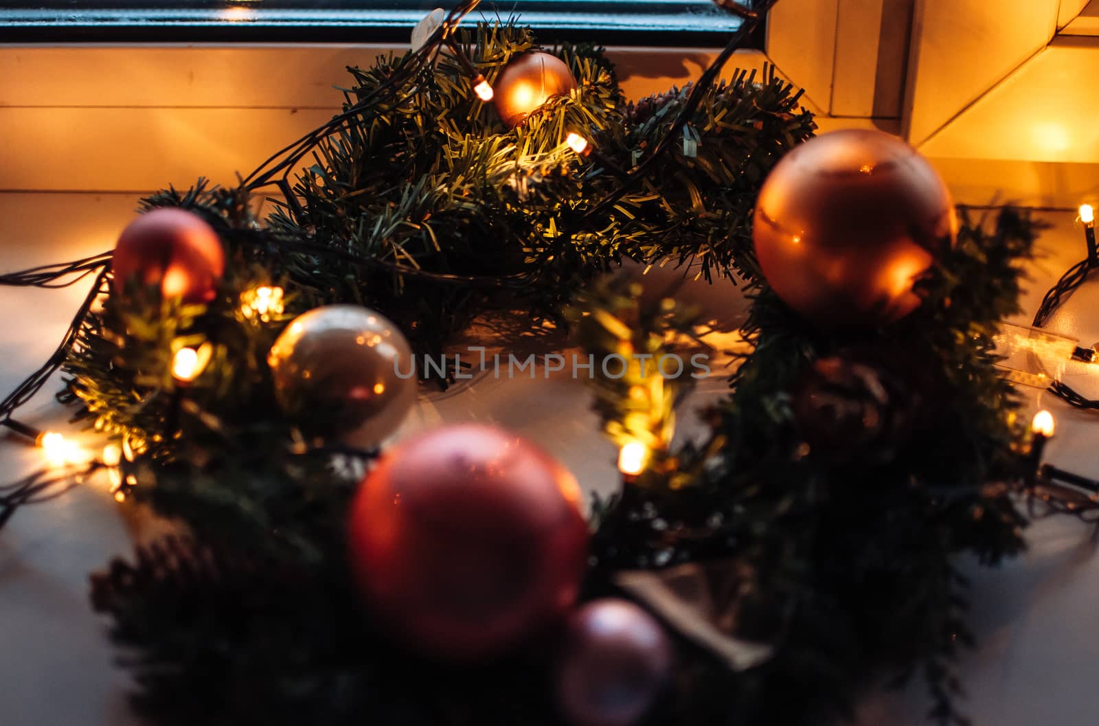 Decorated wreath of Christmas tree close-up. Red balls and garland backlit with lanterns. New Year's baubles macro photo with bokeh. Winter holiday light decoration by Alla_Morozova93