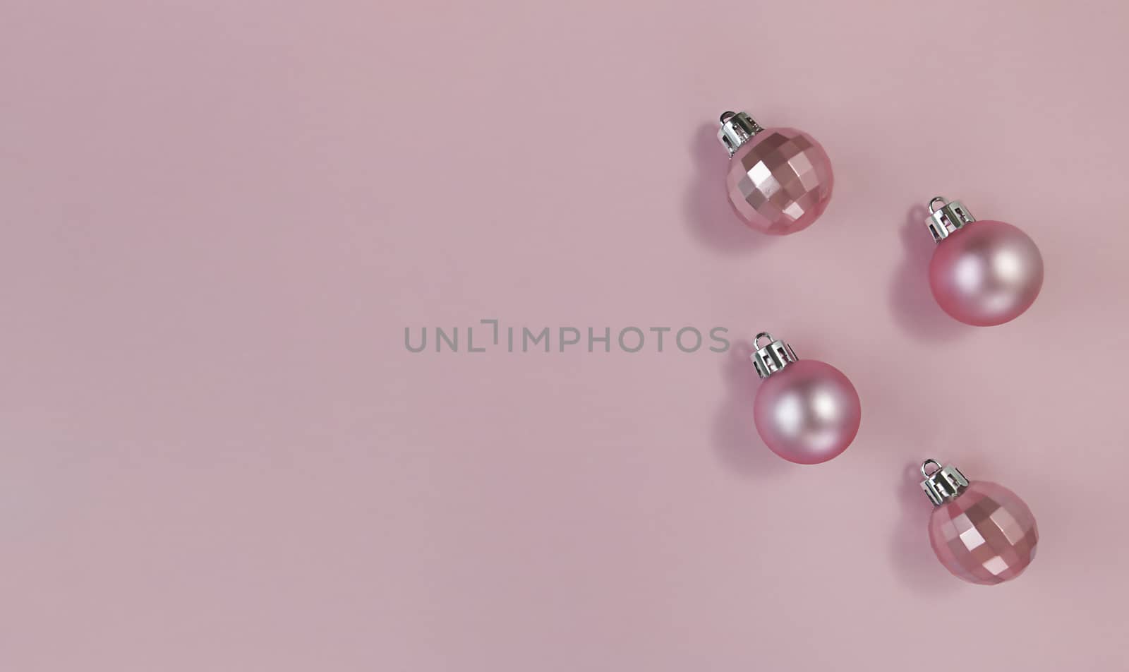 Pink Christmas balls on pastel paper. Simple flat lay with copy space.