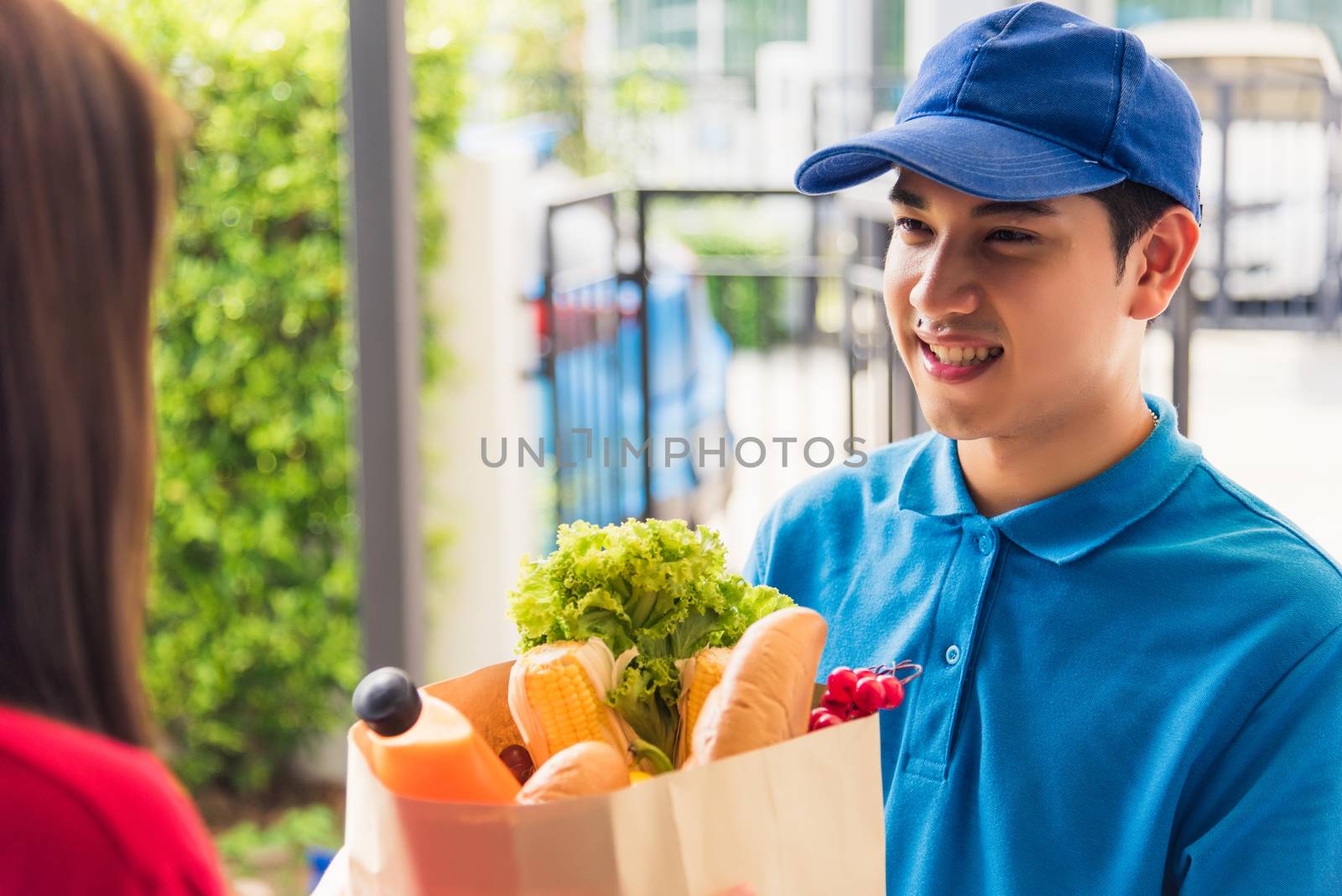 Delivery man making grocery giving fresh food to woman customer by Sorapop