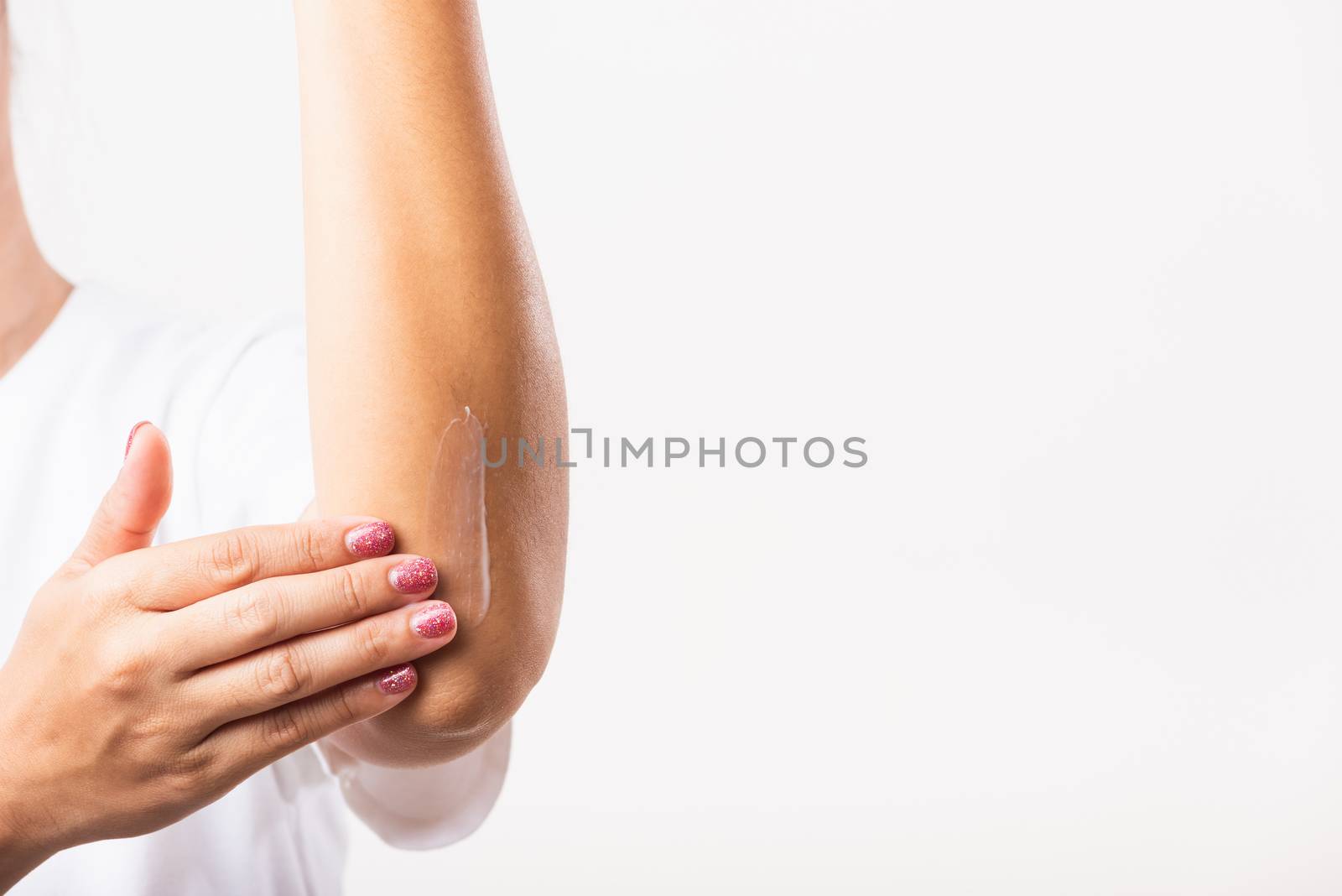 Closeup young Asian woman applies lotion cream on her elbow, studio shot isolated on white background, Healthcare medical and hygiene skin body care concept