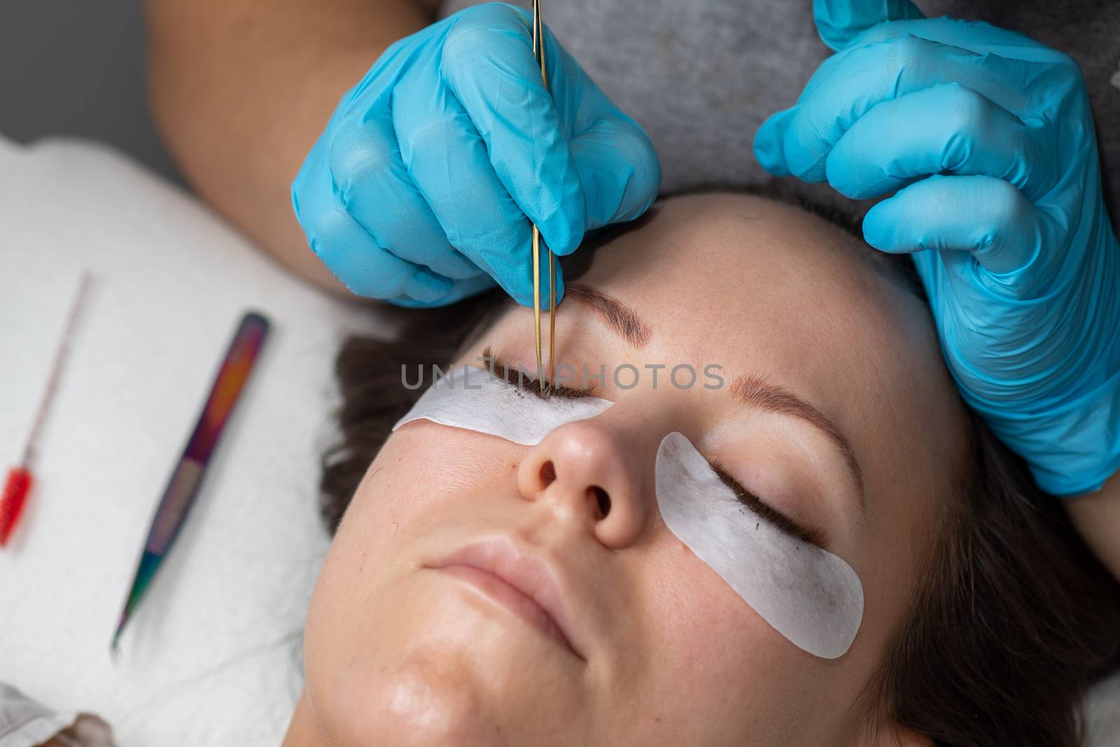 Treatment beauty procedure of upgrade Eyelashes Extension with tweezers Woman Eyes with long extended lashes