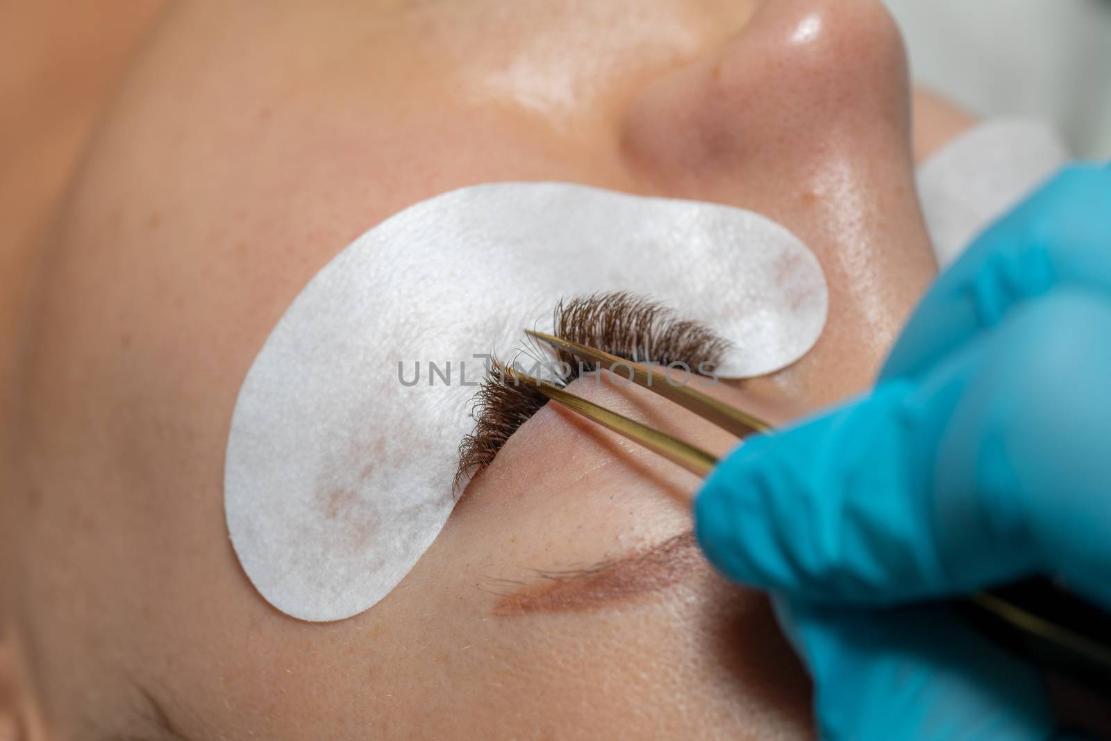 Treatment beauty procedure of upgrade Eyelashes Extension with tweezers Woman Eyes with long extended lashes