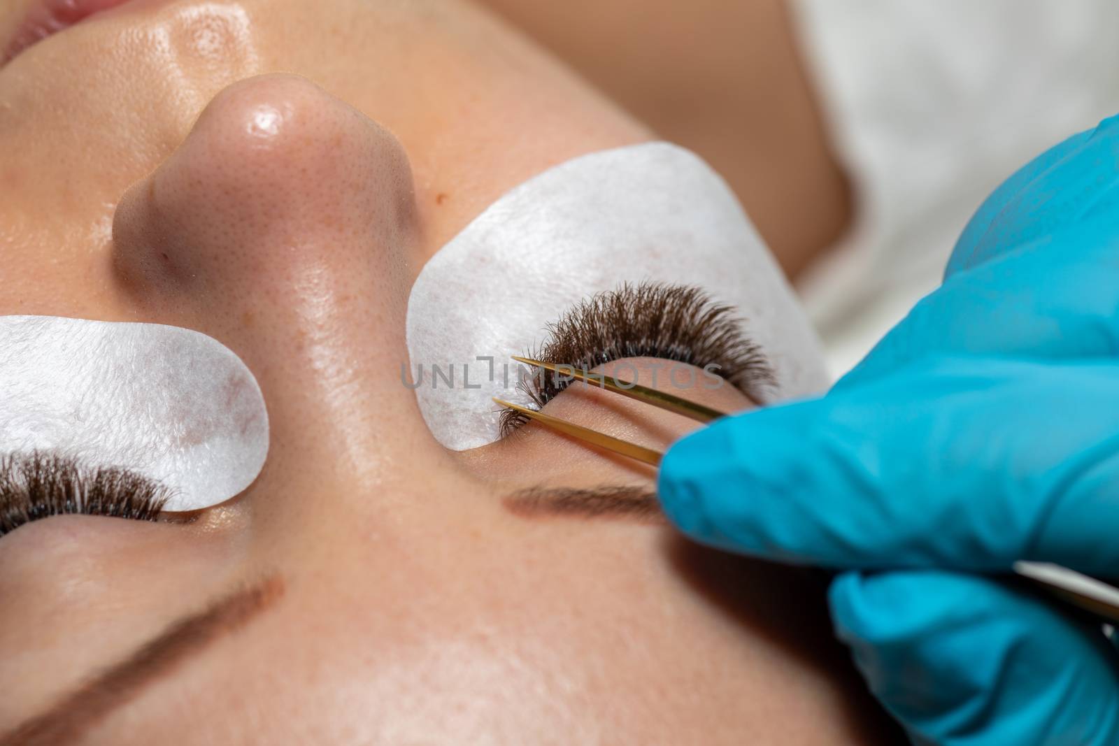 Treatment of Eyelash Extension with tweezers. Woman Eyes with lo by adamr