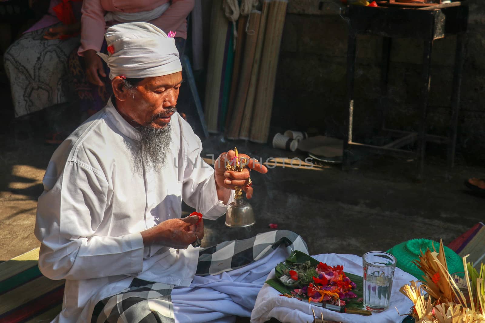 Hindu priest wearing a white uniform was carrying out a religious ceremony with a melodious chime and a beautiful and peaceful chant.