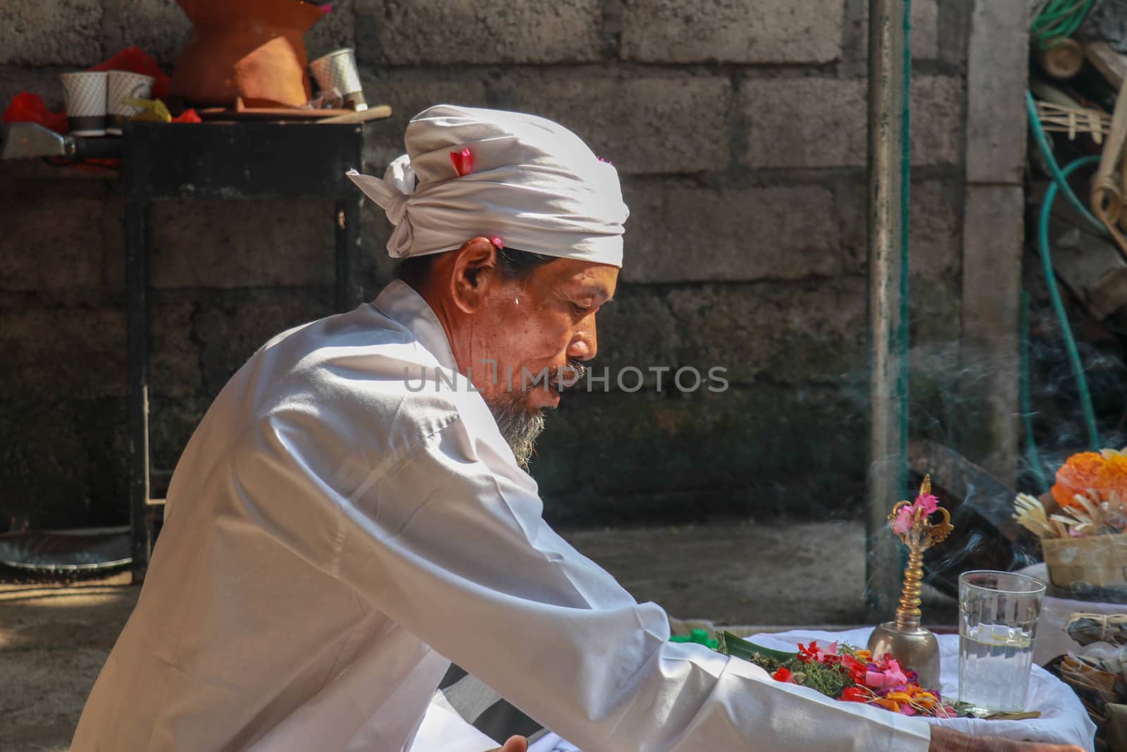 Closeup photograph of a Balinese Hindu high priest conducting a Ngaben ceremony in Ubud, Denpasar, Bali, Indonesia.