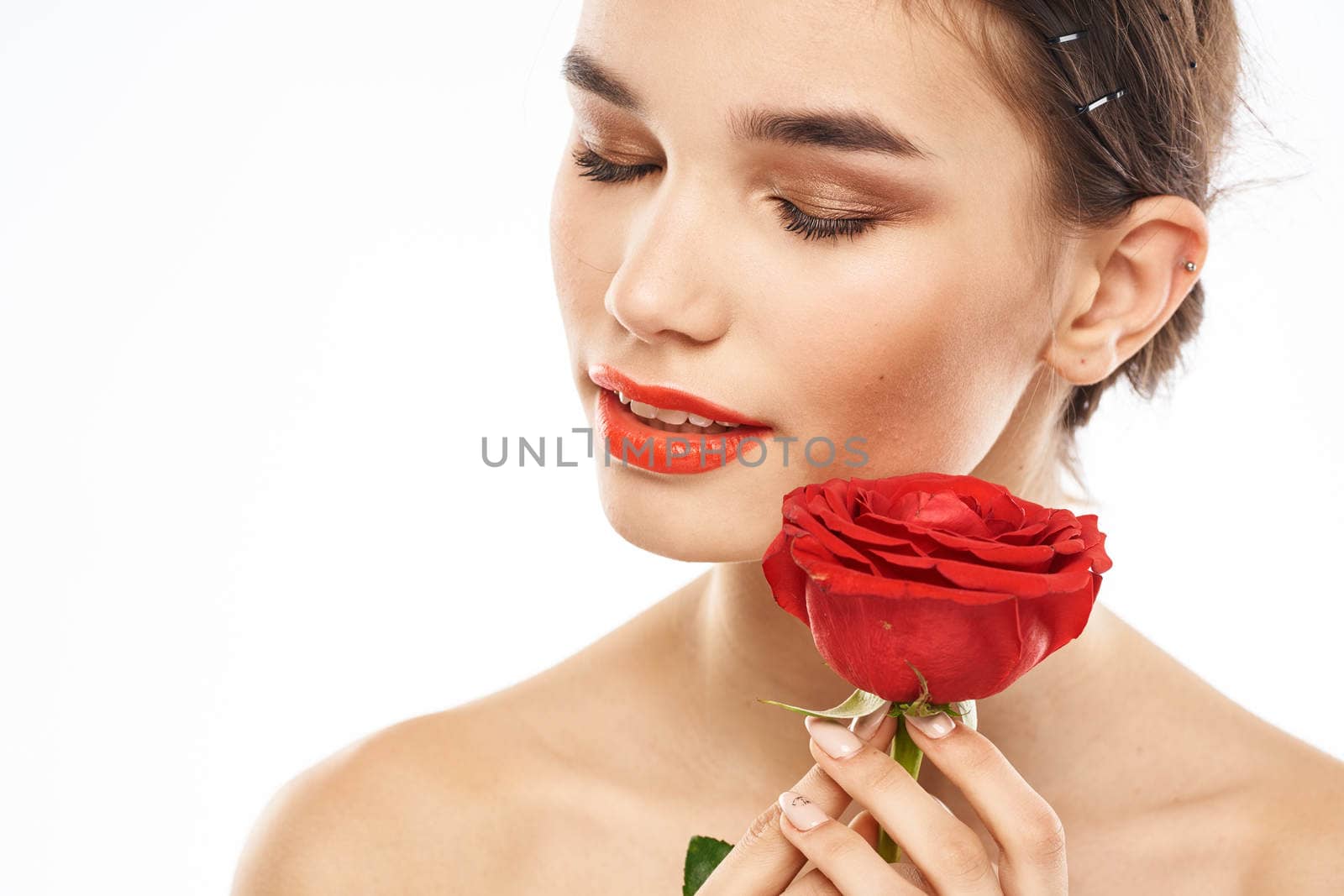 Beautiful woman with red rose near face makeup naked shoulders portrait. High quality photo