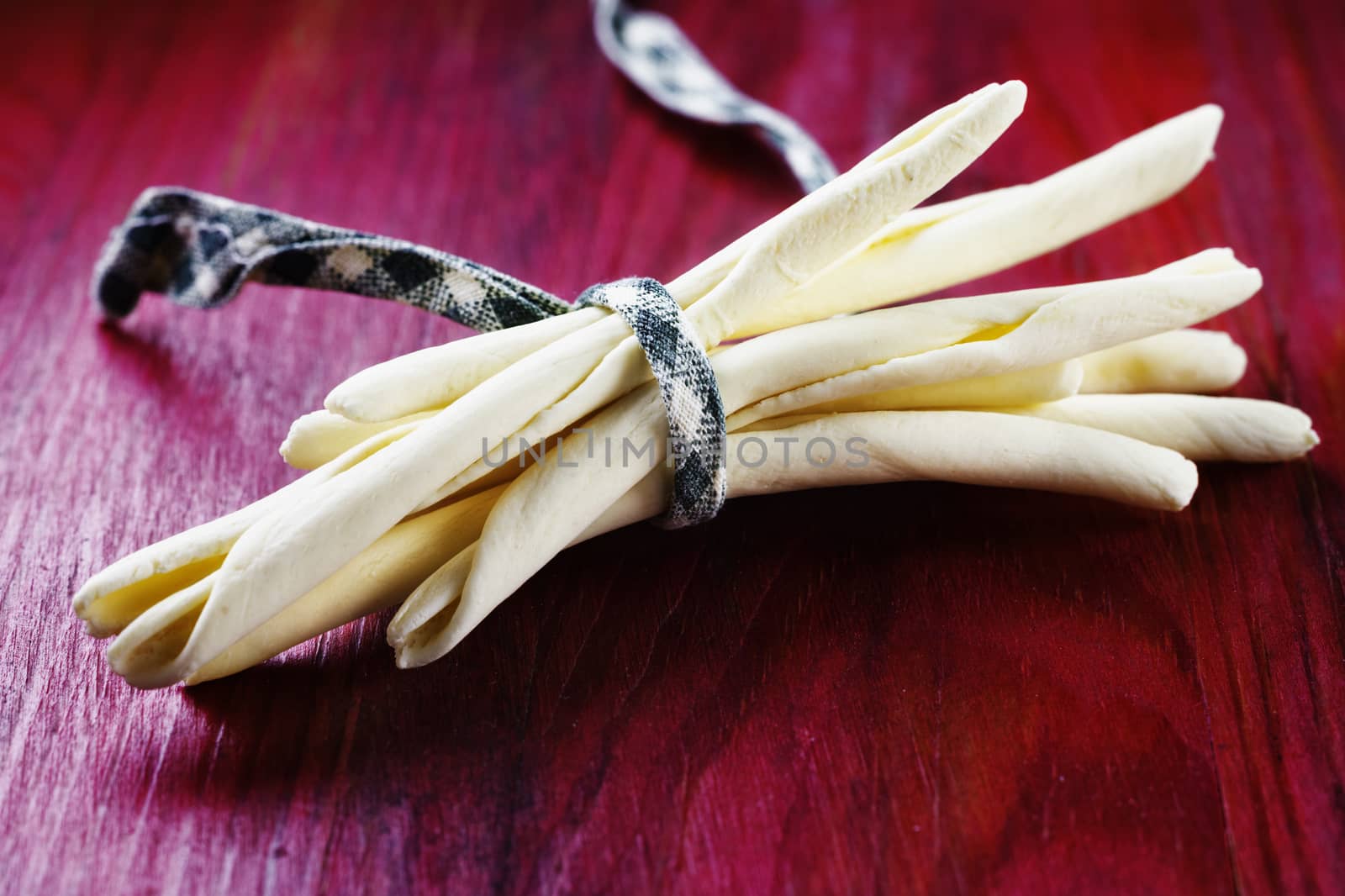 Italian pasta called maccheroni calabresi on red wooden background ,long and thick pasta made with durum wheat semolina and water ,tipical pasta of Calabrian tradition