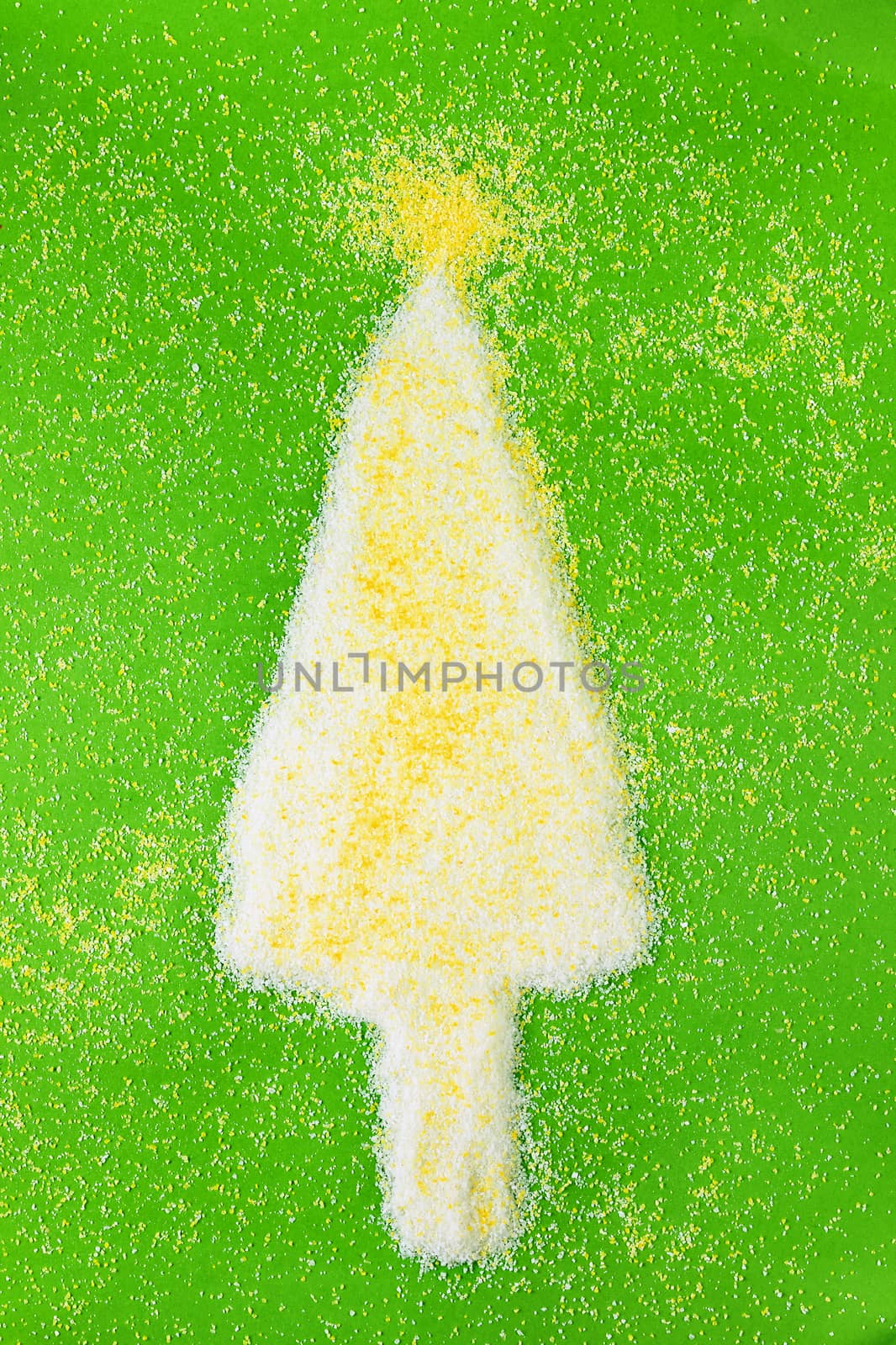 Beautiful christmas tree made using yellow and white grains of cornmeal on green  background ,several grains on the background , yellow star on top 