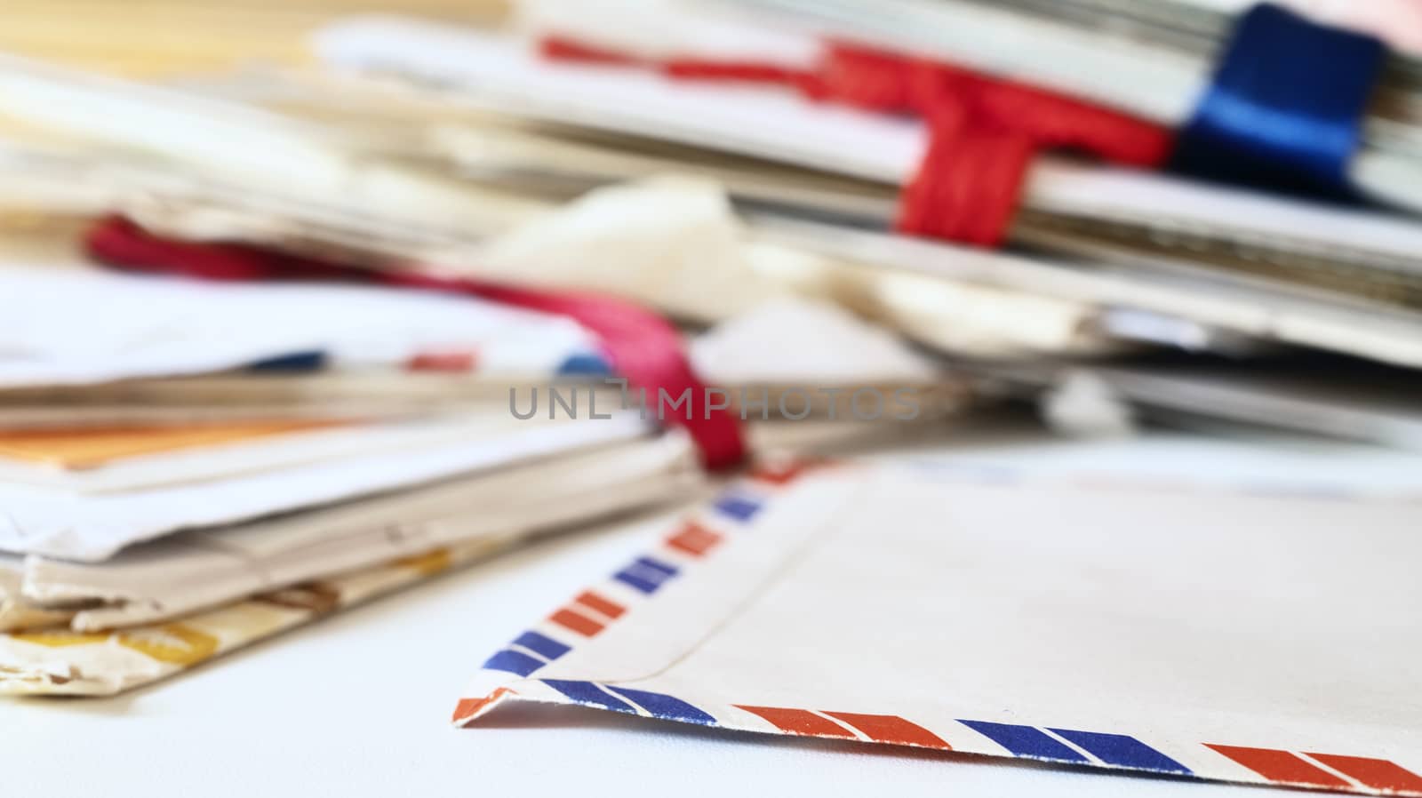 Old letters on table , in the foreground an opened airmail envelope , in the background stacks of letters  lay one above the other ,clean up and memories 