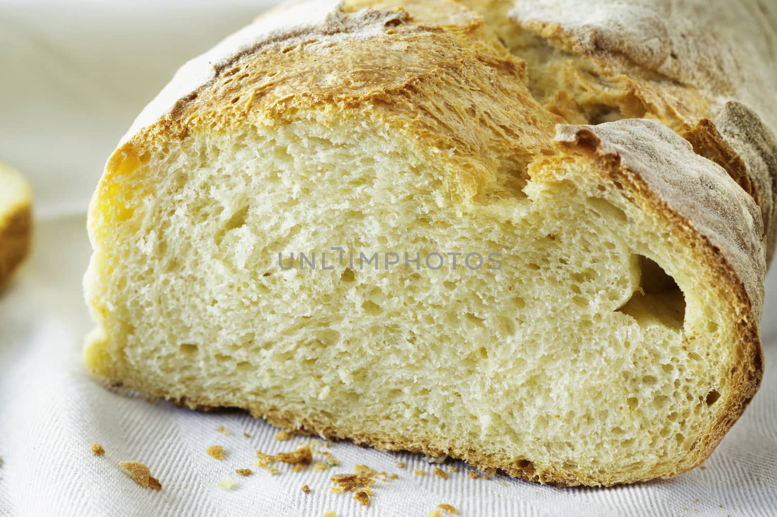 Freshy baked piece of  bread on white  cotton cloth , bread crumbs in the foreground ,beautiful bread crust  ,durum wheat bread