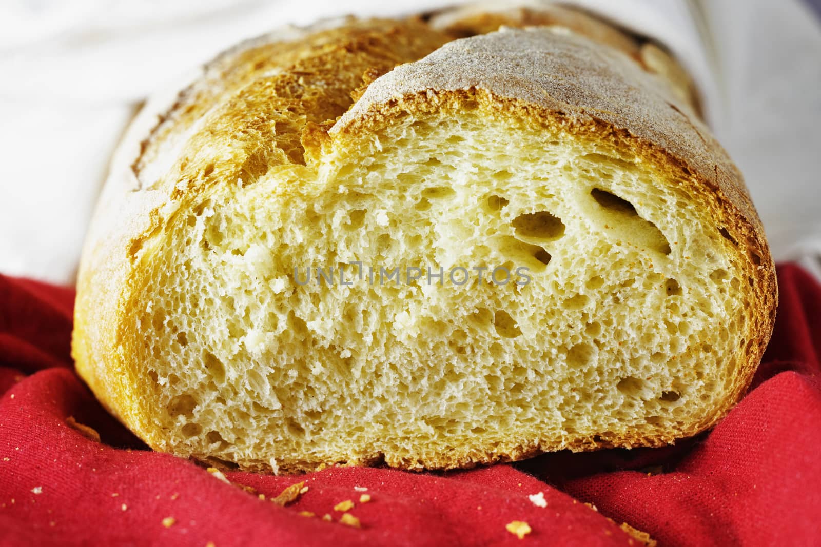 Freshy baked cut bread on red and white cloth  ,bread crumbs in the foreground ,durum wheat bread