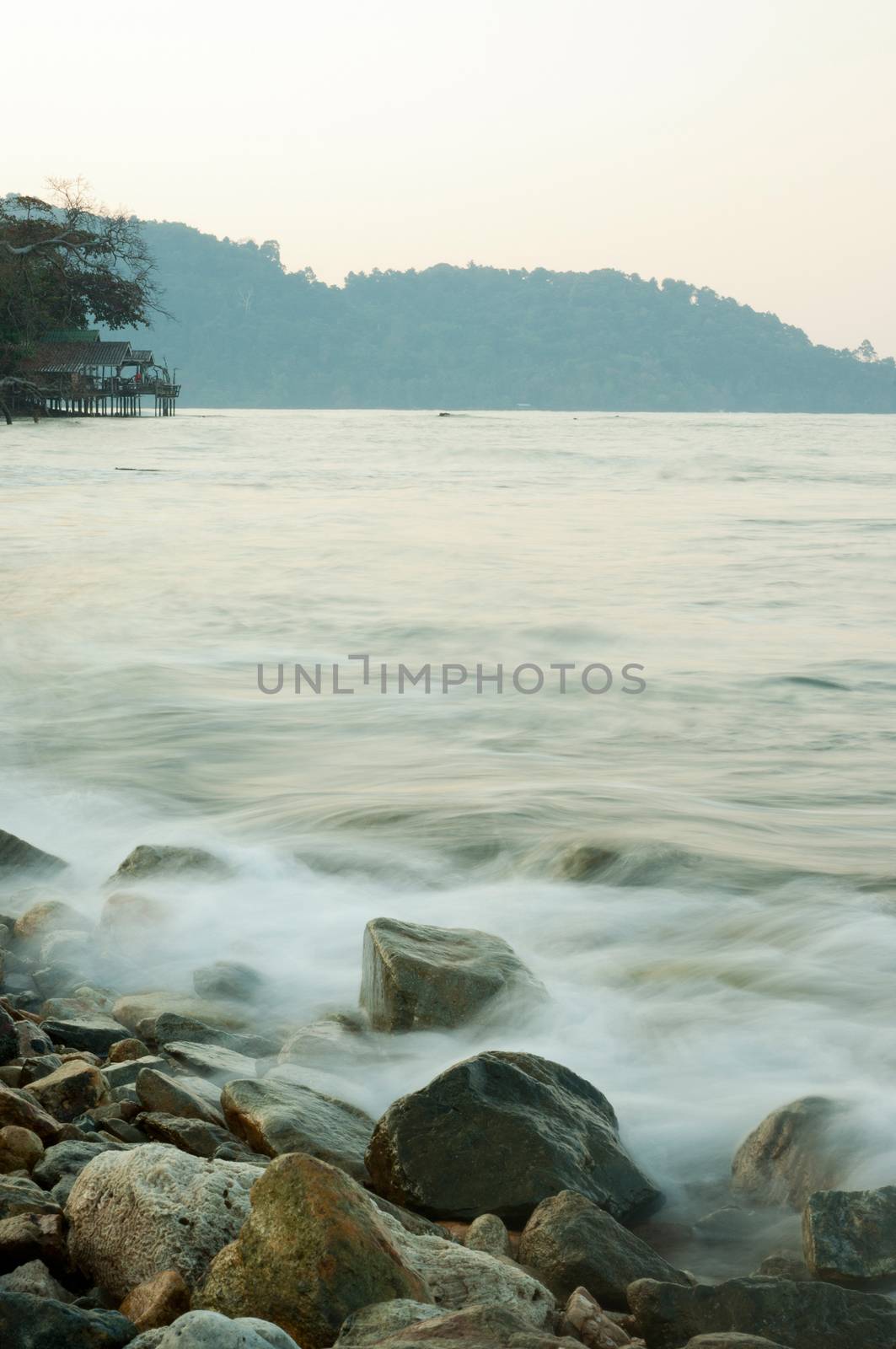 Soft waves on a rocky beach in the morning by Satakorn