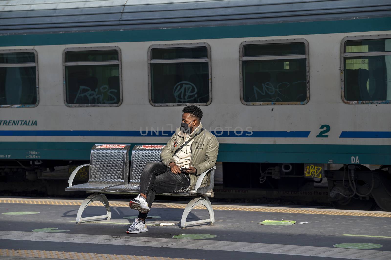 terni,italy november 03 2020:black boy waits for the train with medical mask due to corona virus