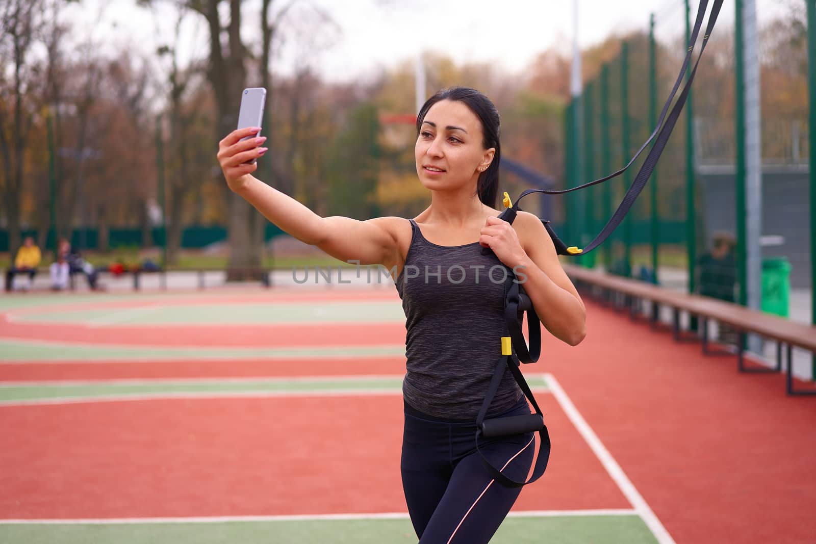 Girl athlete training using trx on sportground. Mixed race young adult woman do workout with suspension system. Healthy lifestyle. Stretching outdoors playground. by andreonegin