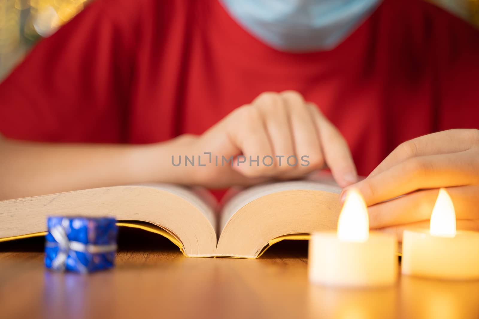 Close up shot of hands reading bible with candles in front on decorated Christmas background during xmas festival celebration by lakshmiprasad.maski@gmai.com