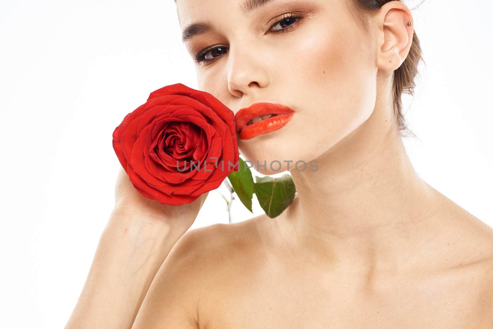 charming brunette girl with makeup on her face and a red rose in her hand. High quality photo