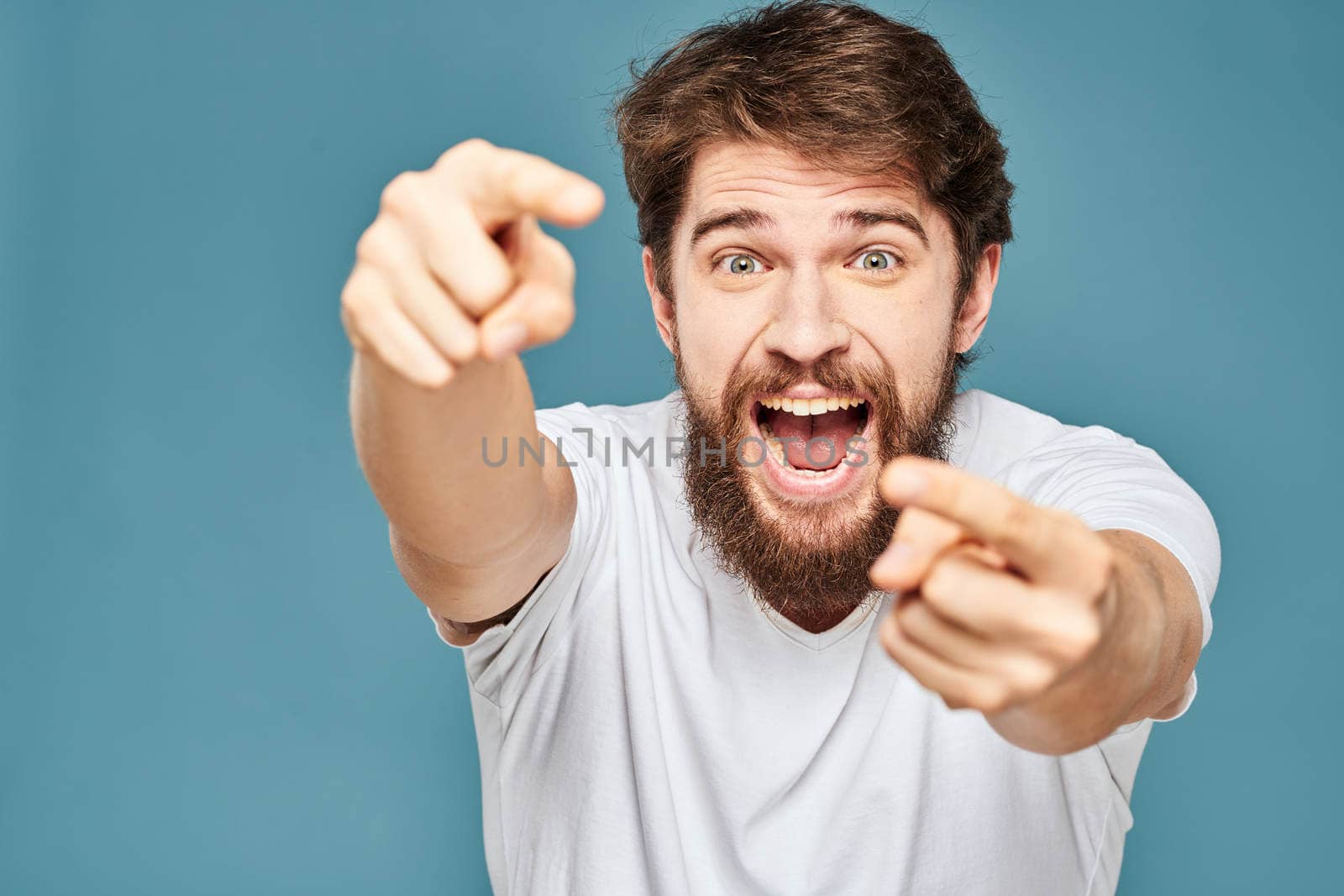 emotional man gesturing with hands lifestyle fun white t-shirt blue isolated stock. High quality photo