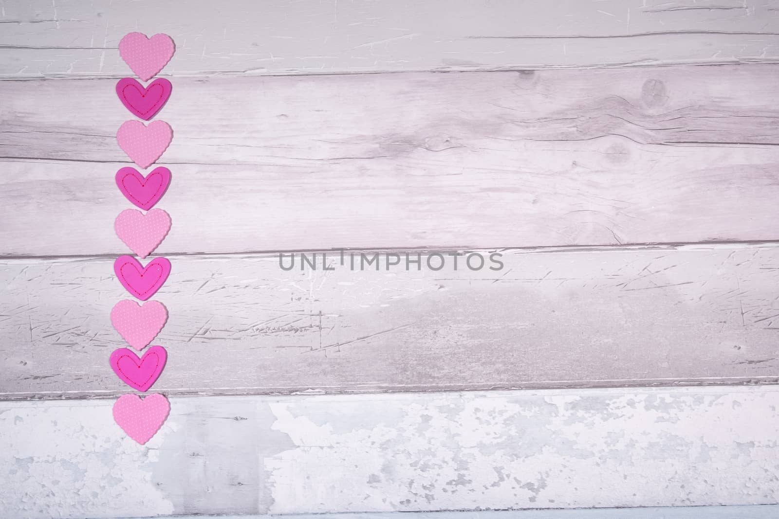 Pink felt hearts on a background of old wooden planks resembling an old parquet floor. Concept of valentines day and love in general.