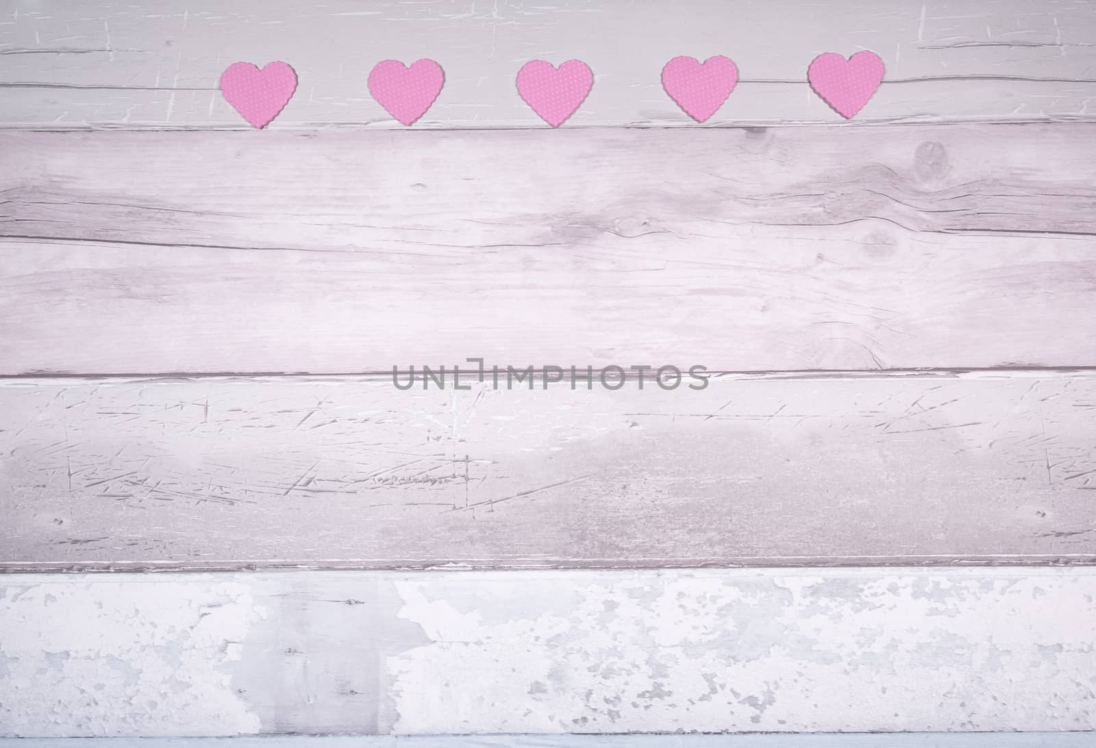 Pink felt hearts on a background of old wooden planks resembling an old parquet floor. Concept of valentines day and love in general.