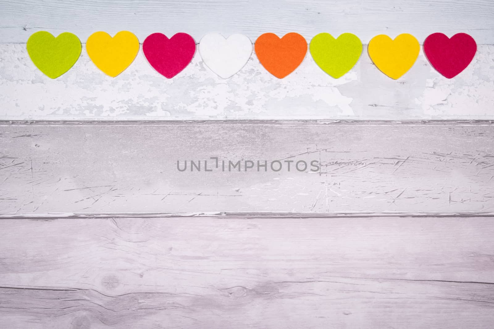 Colorful felt hearts on a background of old wooden planks resembling an old parquet floor. Concept of valentine's day and love in general.