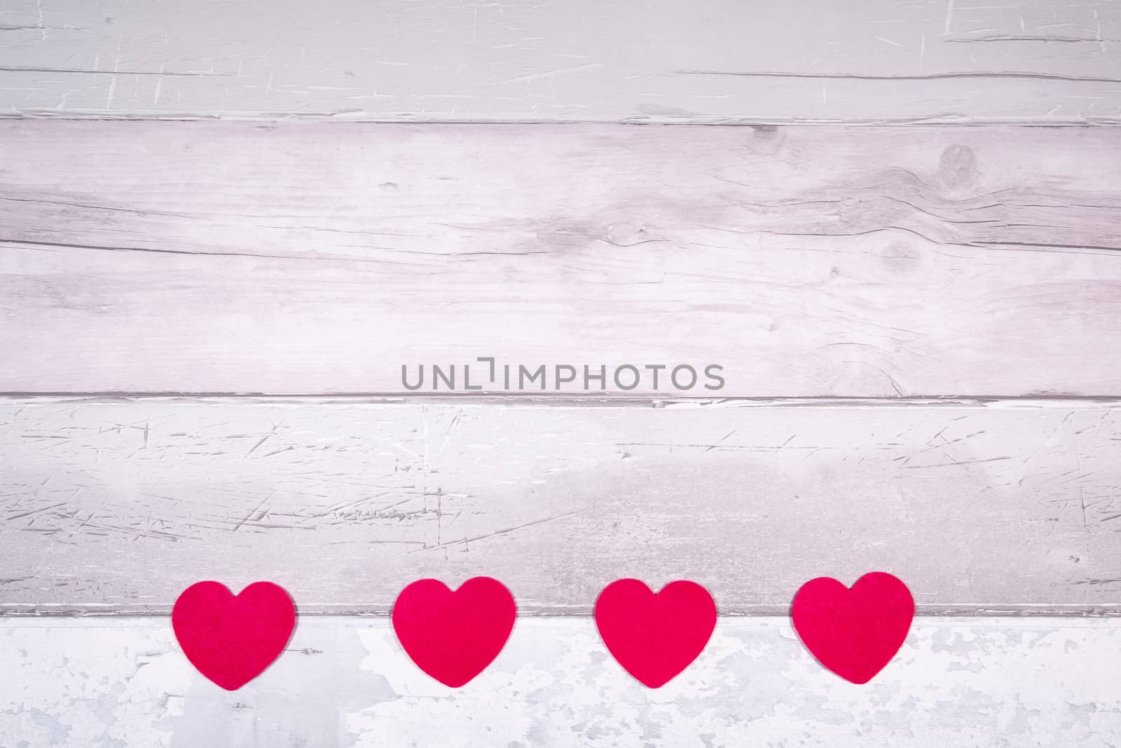 Red felt hearts on a background of old wooden planks resembling an old parquet floor. Concept of valentines day and love in general.