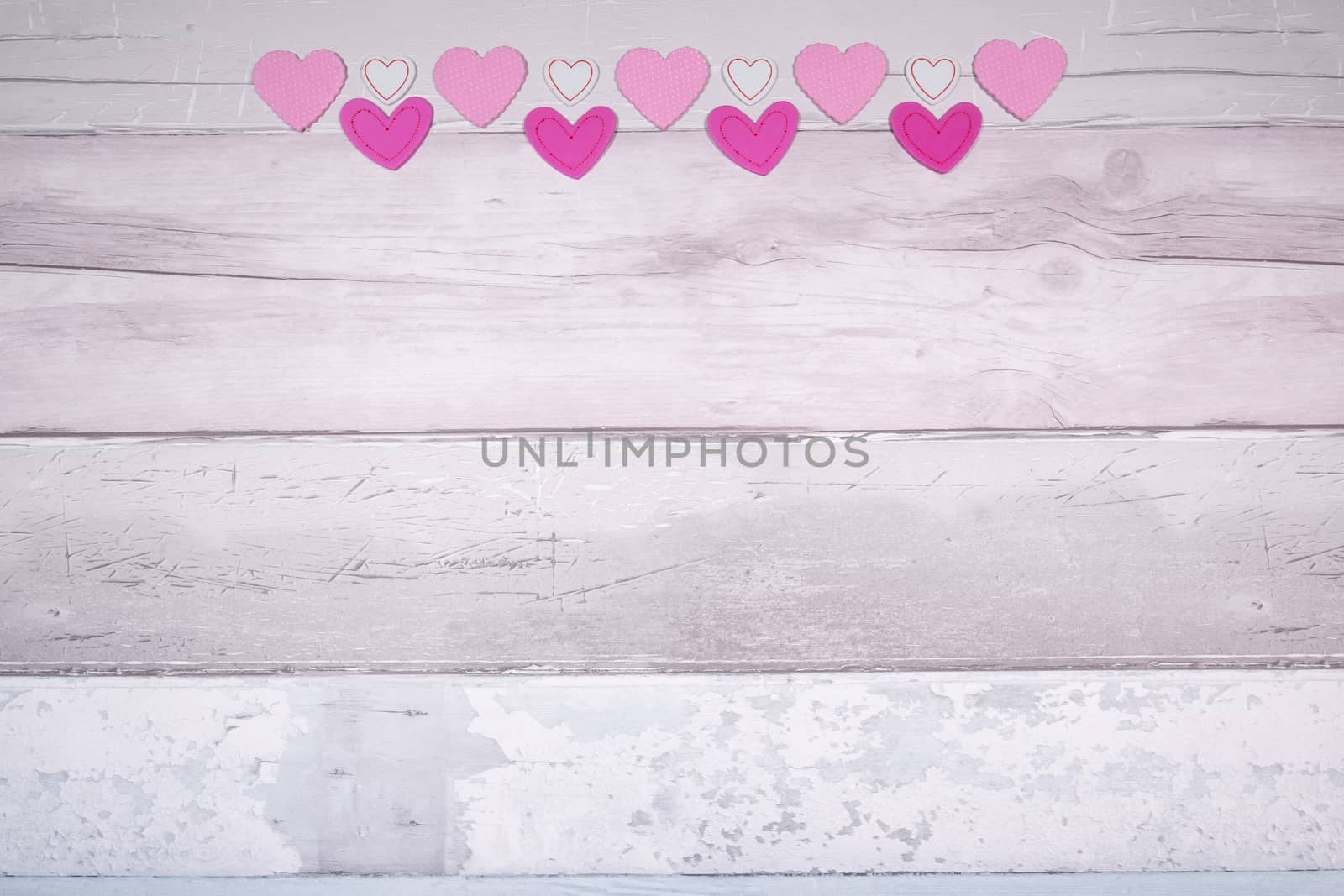 Pink felt hearts on a background of old wooden planks resembling an old parquet floor. Concept of valentines day and love in general.