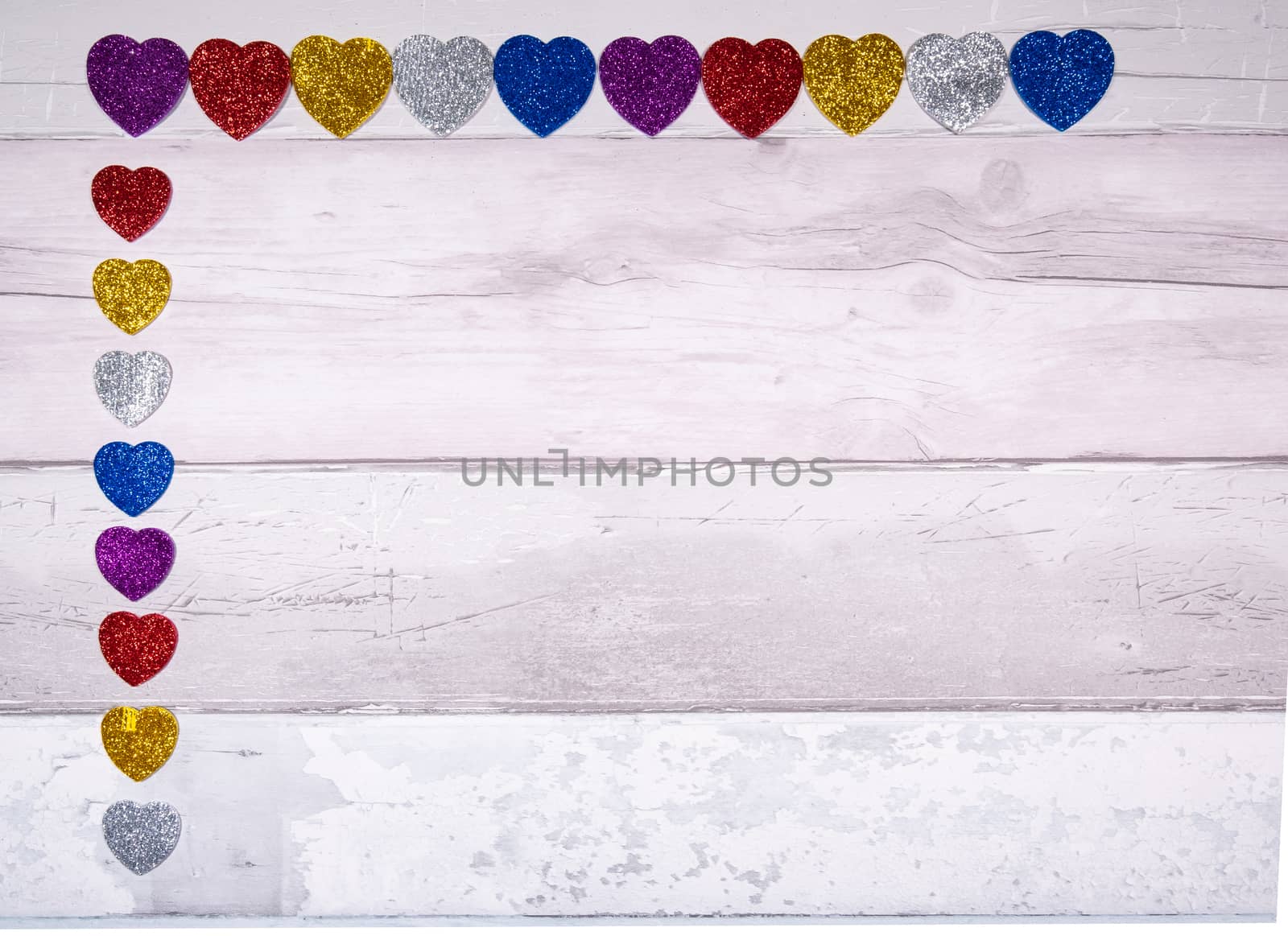 Hearts with glitter of all colors on a background of old wooden planks resembling an old parquet floor. Concept of valentines day and love in general.