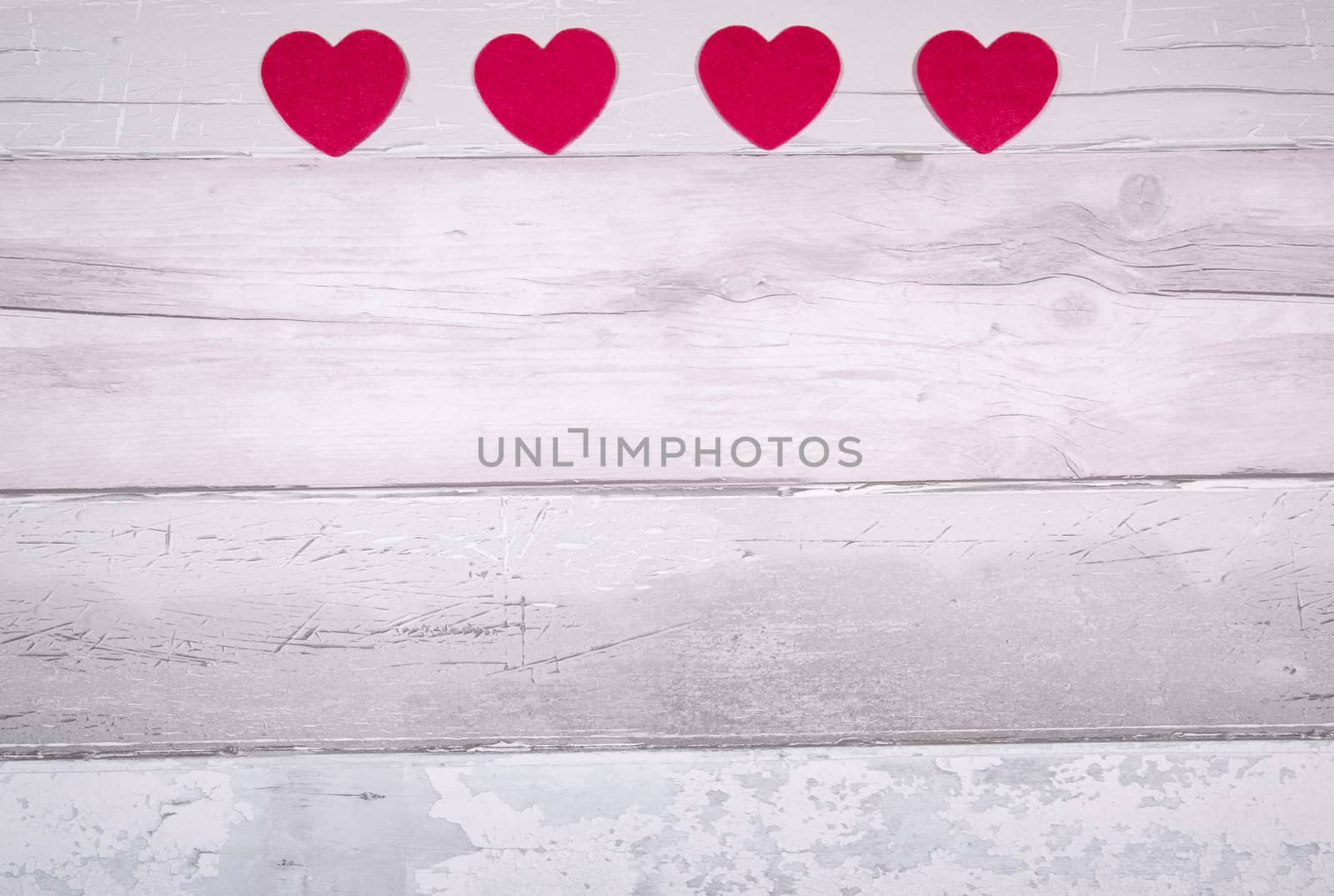 Red felt hearts on a background of old wooden planks resembling an old parquet floor. Concept of valentines day and love in general.