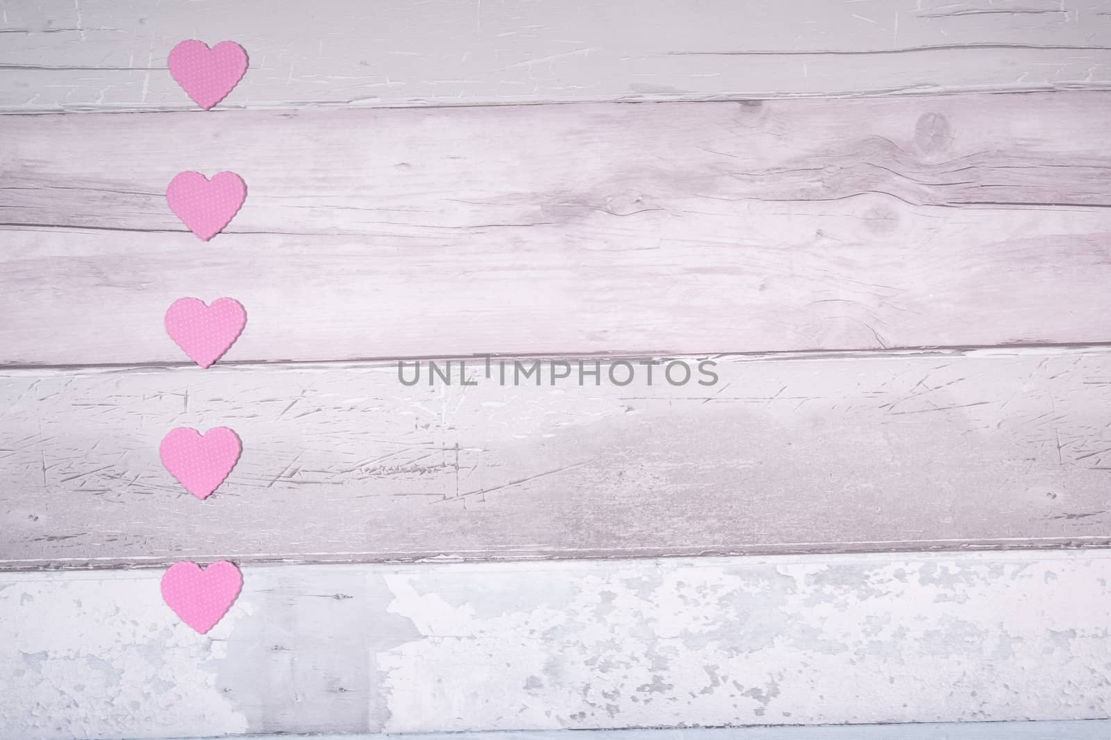 Pink felt hearts on a background of old wooden planks resembling an old parquet floor. Concept of valentines day and love in general.