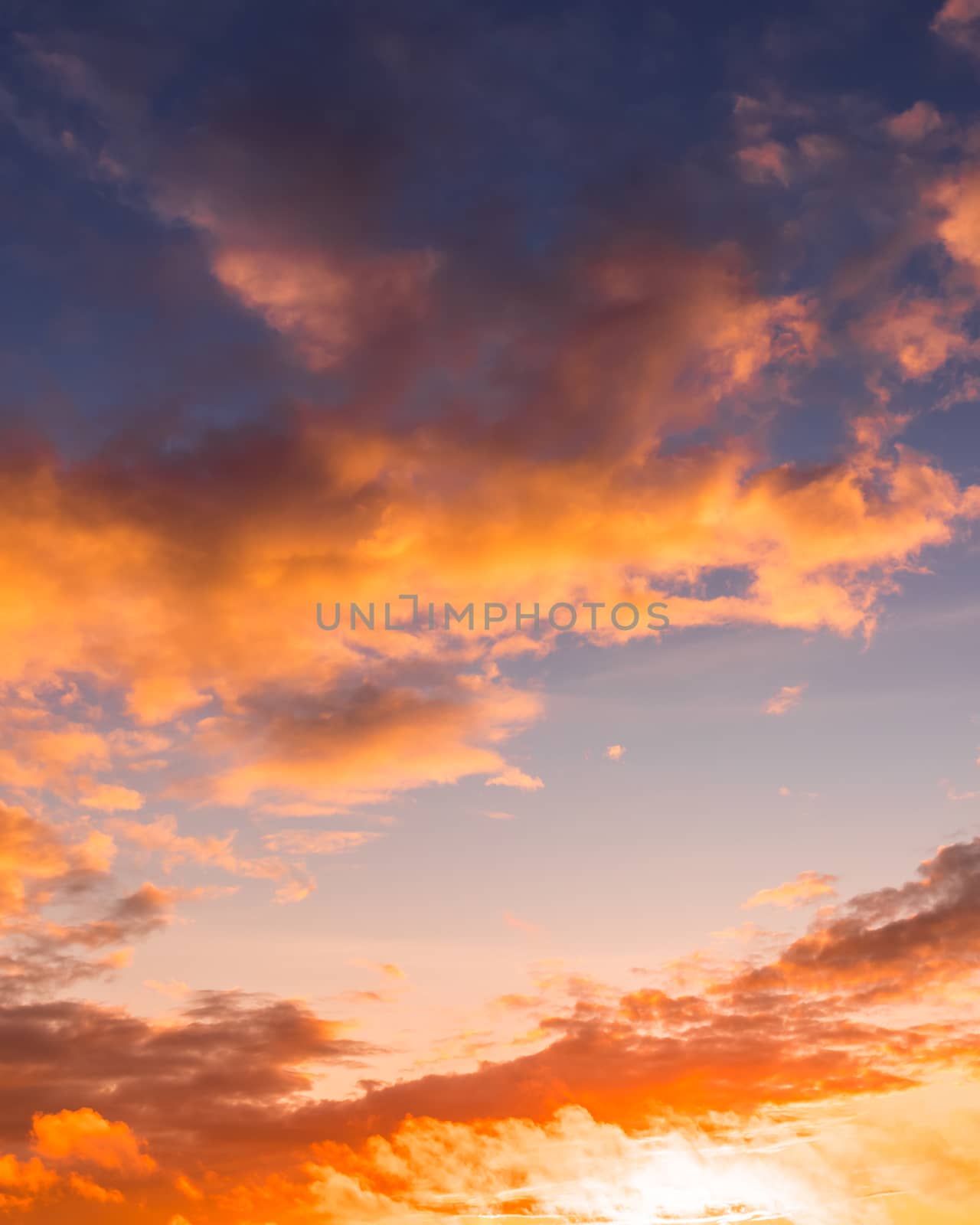 Colorful orange-purple dramatic clouds lit by the setting sun against the evening sunset sky. Cloudscape.