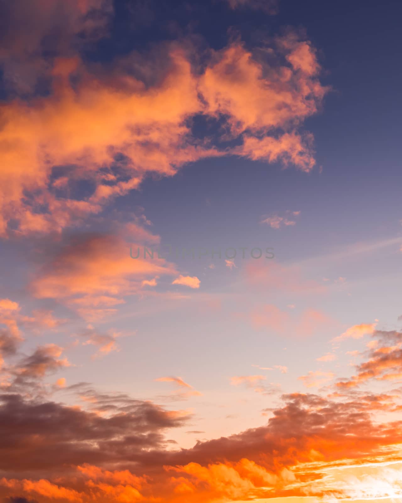 Colorful orange-purple dramatic clouds lit by the setting sun against the evening sunset sky. Cloudscape.