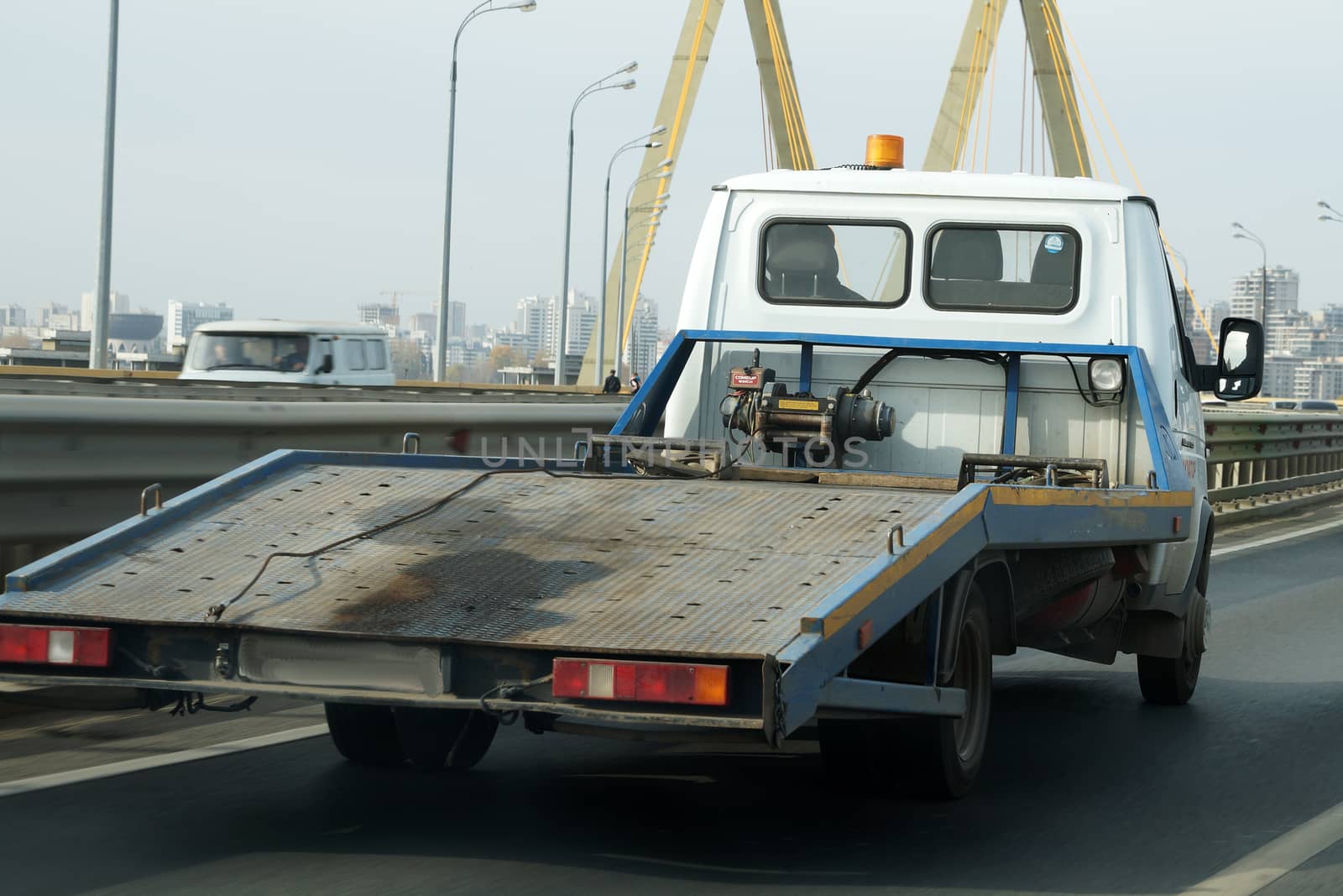 empty tow truck drives down the street, back view.