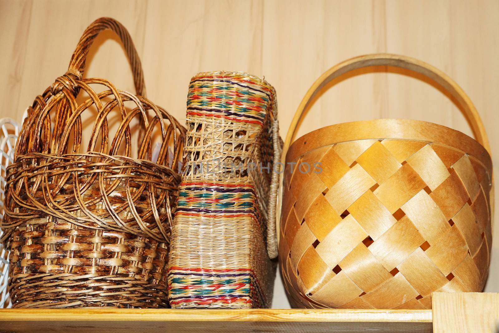 three wicker baskets on a wooden shelf close up
