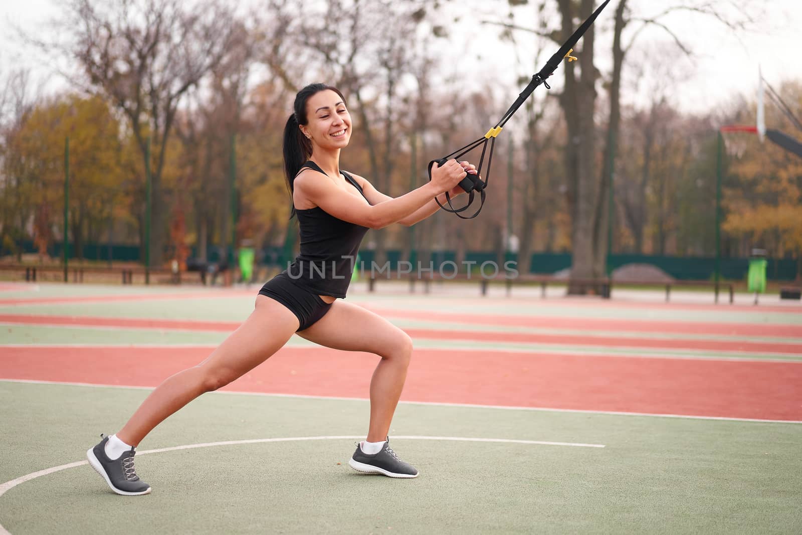 Girl athlete training using trx sportground Mixed race young adult woman workout suspension system Healthy lifestyle Stretching outdoors playground. Make your body machine